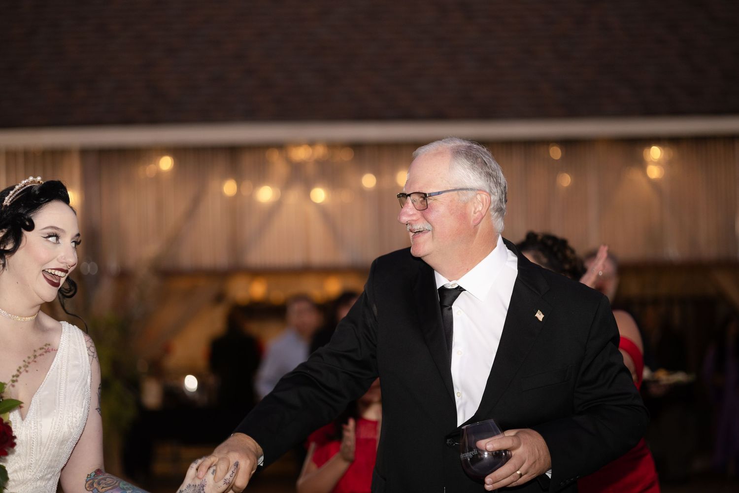 Wedding reception guests dance under warm lighting in a tent venue.
