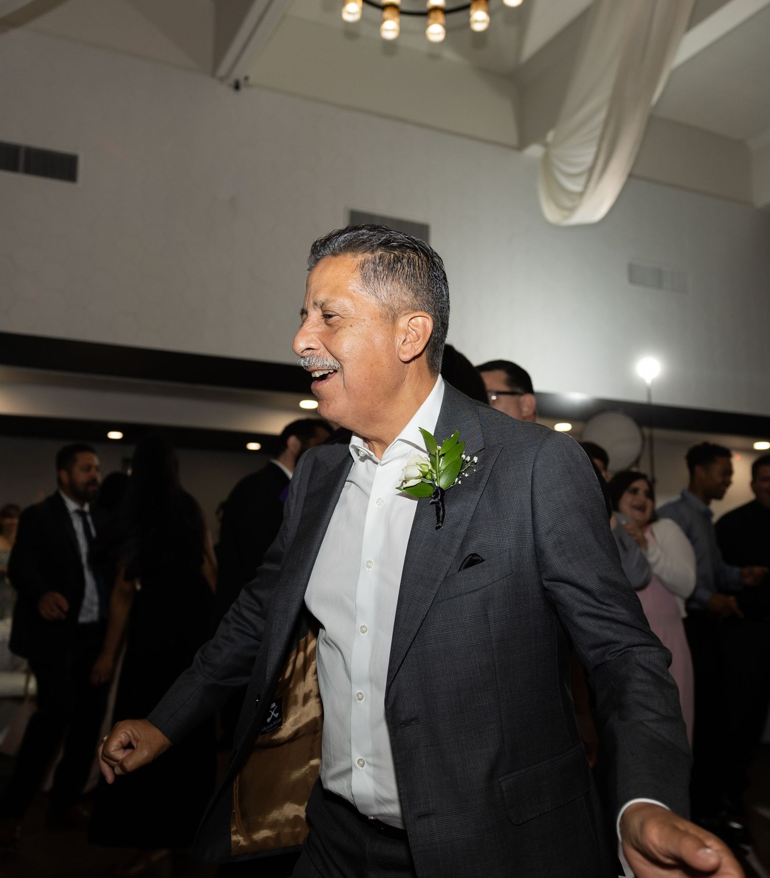Wedding guests dancing and celebrating at an indoor evening reception venue.