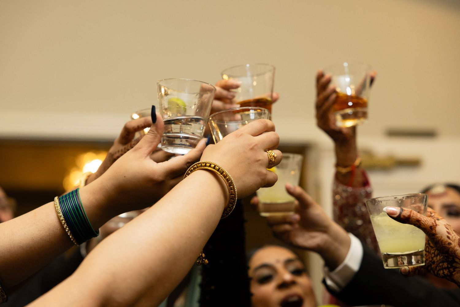 Close-up shots of hands holding drinks and toasting at a celebration.