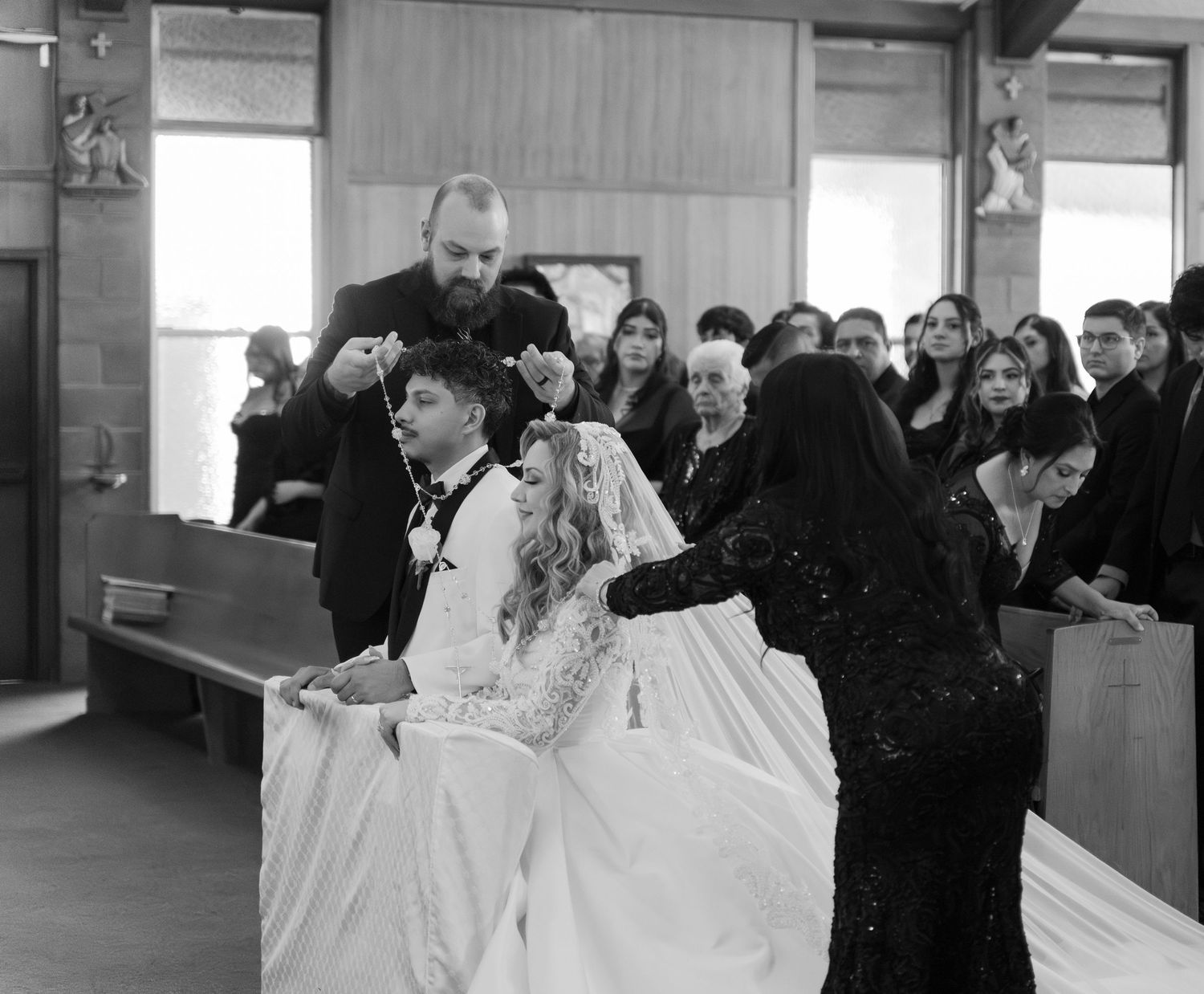 Black and white photo of wedding ceremony with guests seated in church pews.