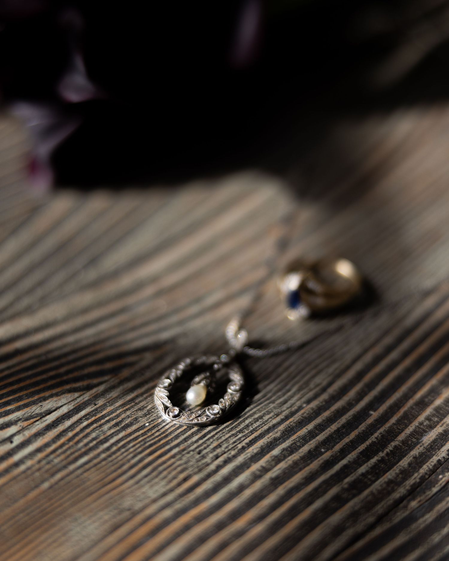 Wedding rings casting shadows on dark wooden surface in dramatic lighting.