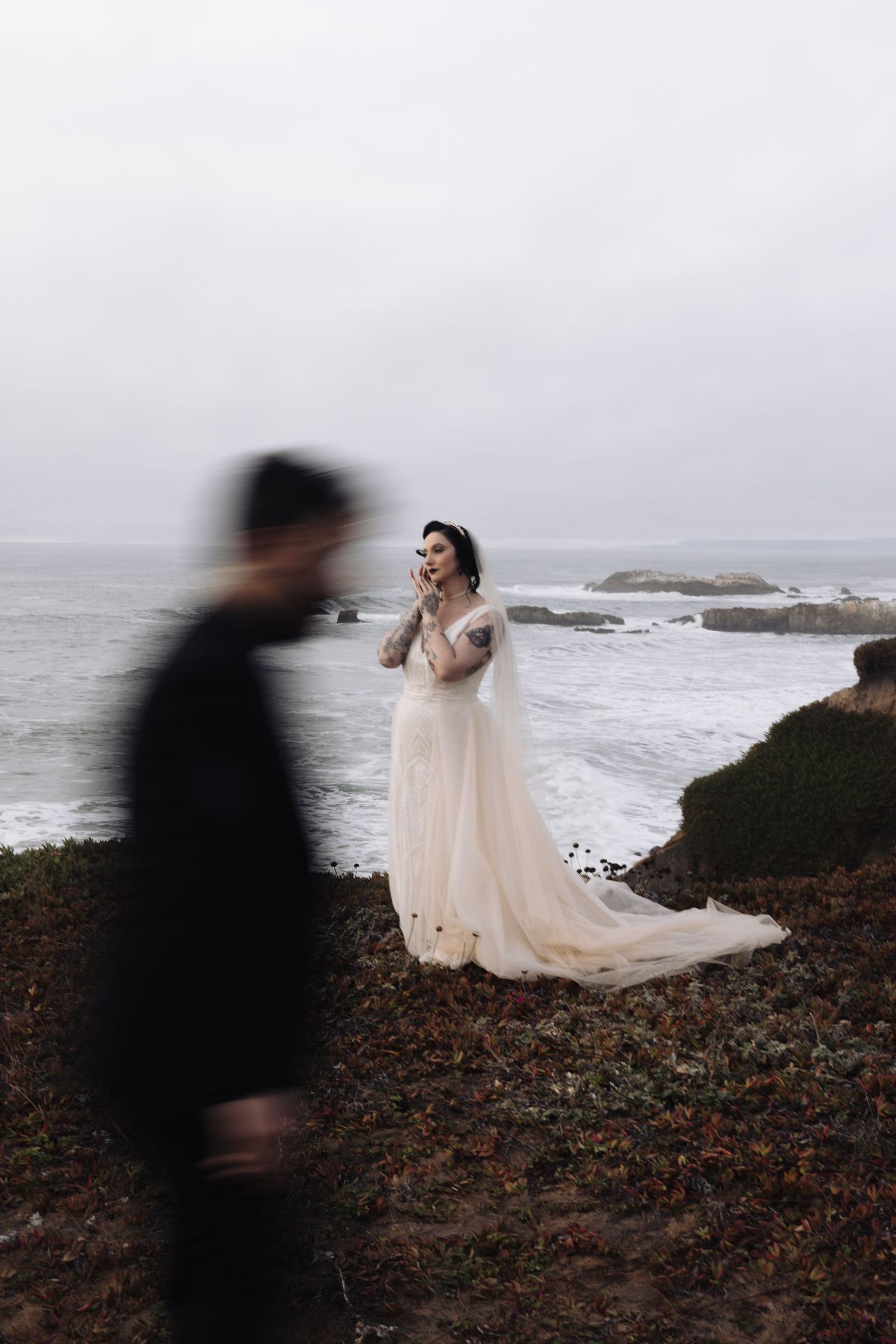 A creative wedding photo with motion blur effect captures movement on a coastal cliff.