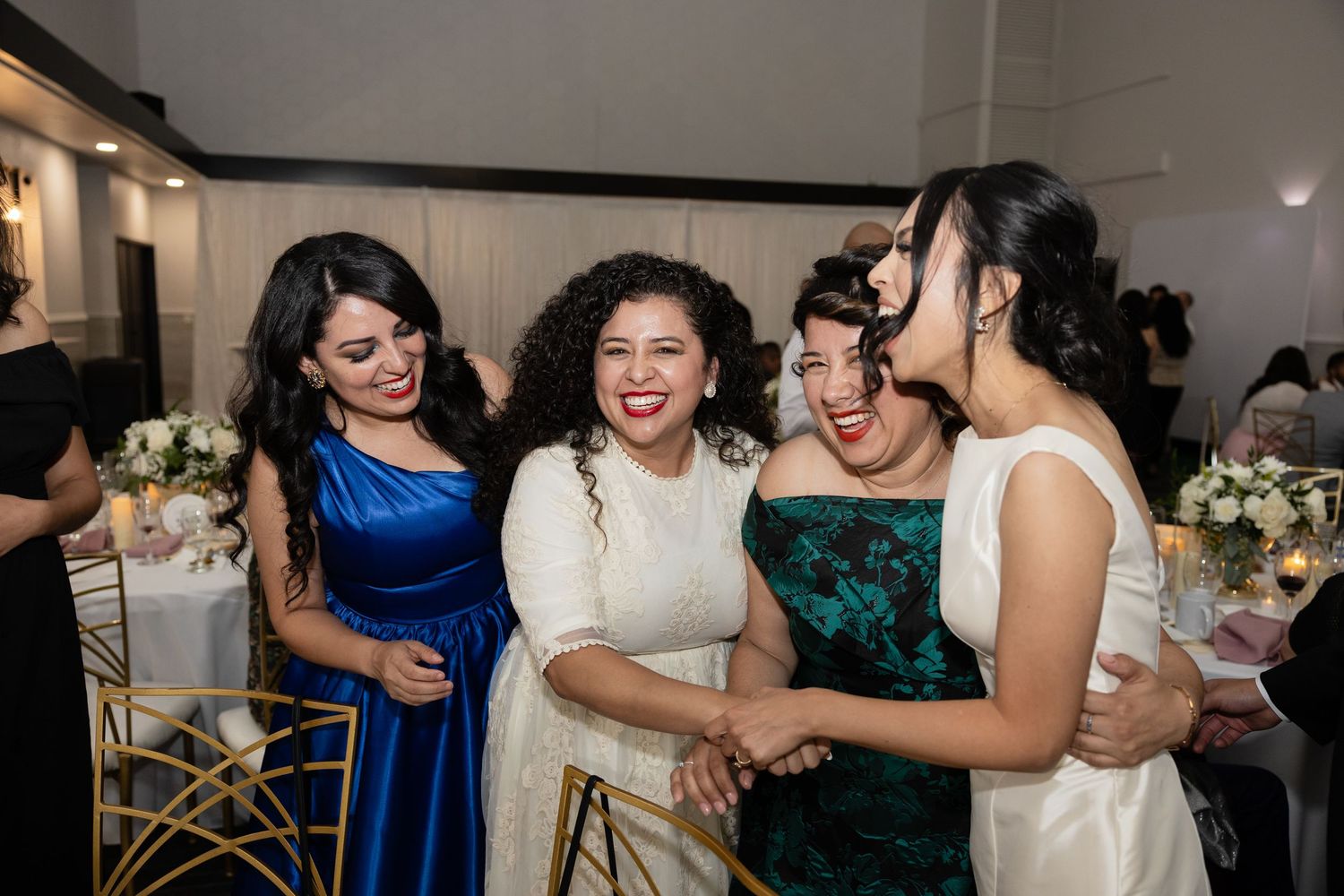 Guests in formal attire dancing and celebrating at an elegant indoor wedding reception.