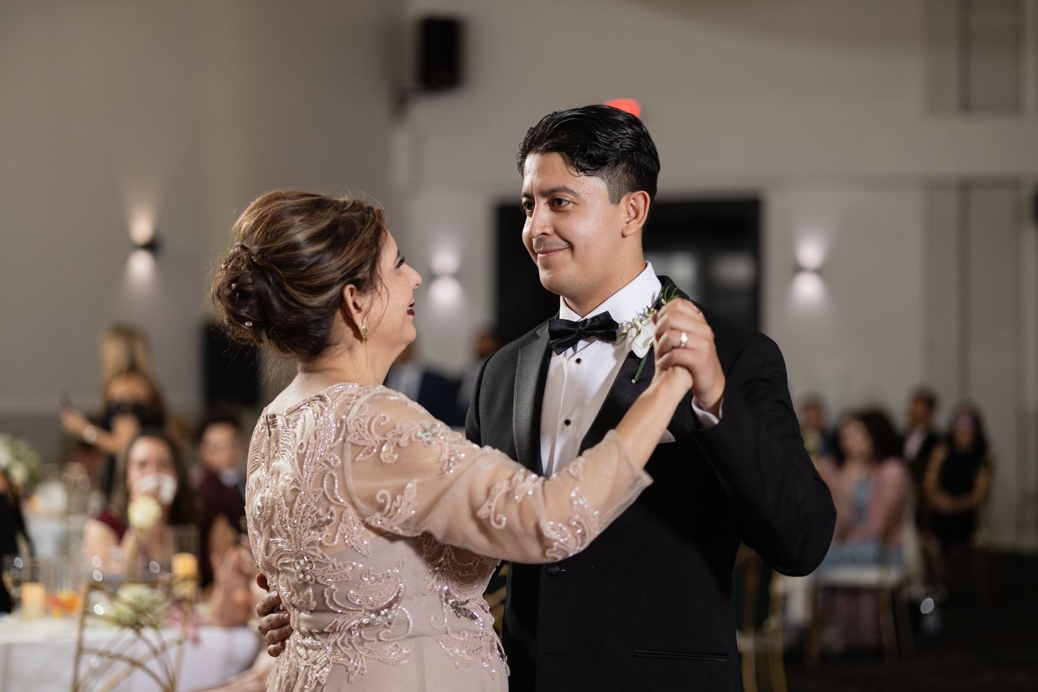 Formal dance partners embrace during an elegant indoor wedding reception.