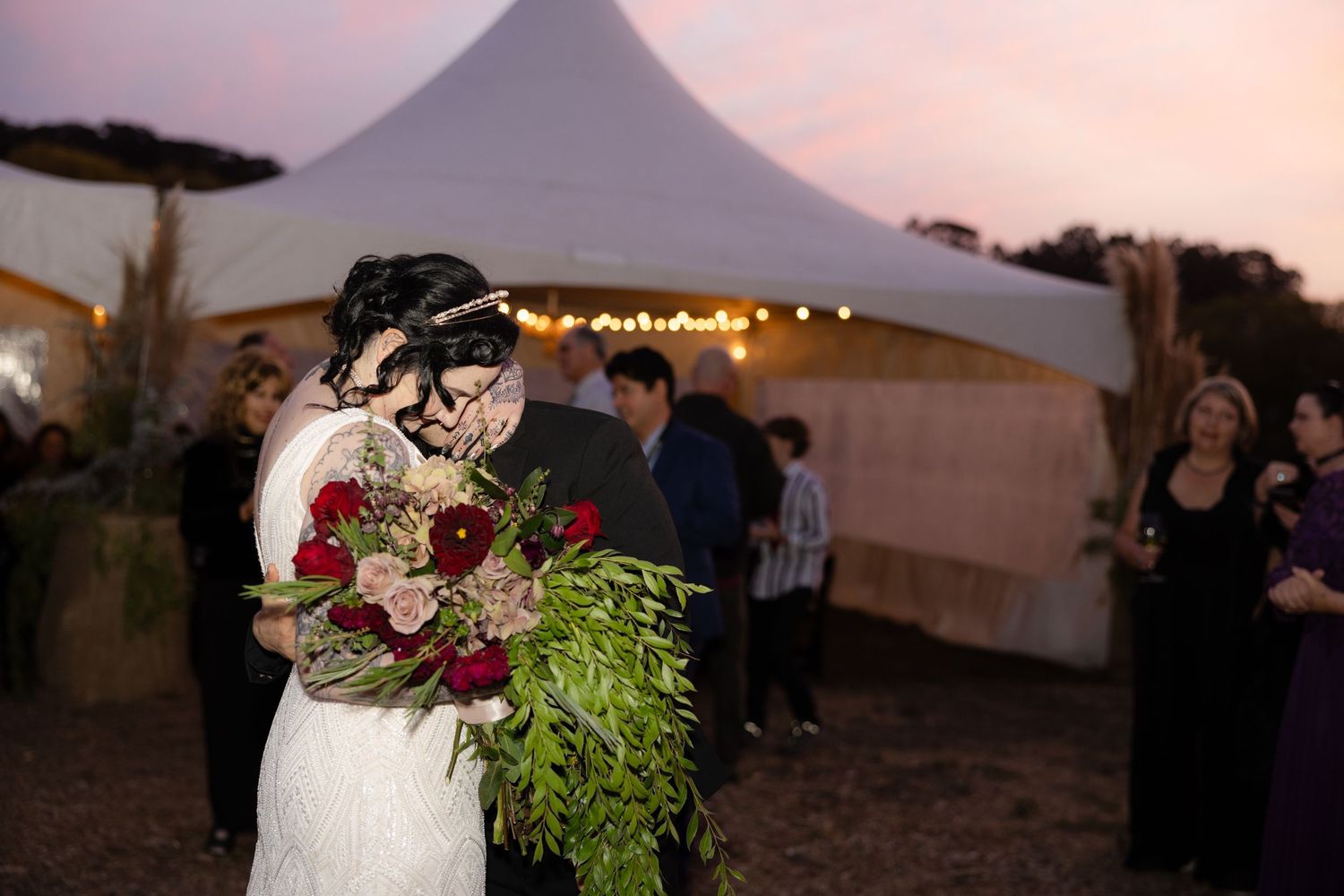 Sunset wedding reception with guests celebrating under tented area.