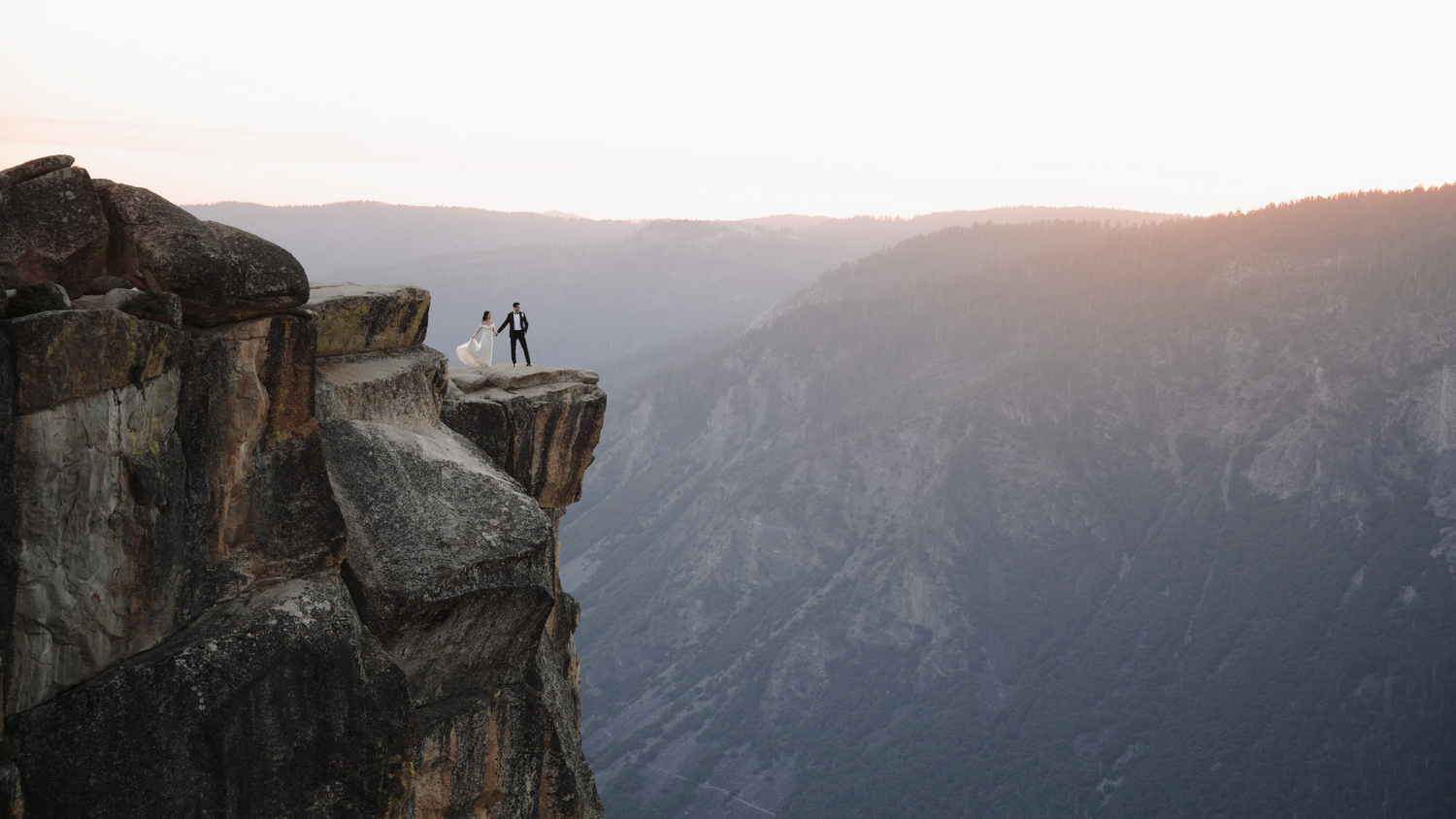 Dramatic sunset view of Taft Point in Yosemite with steep cliffs and mountain ranges.