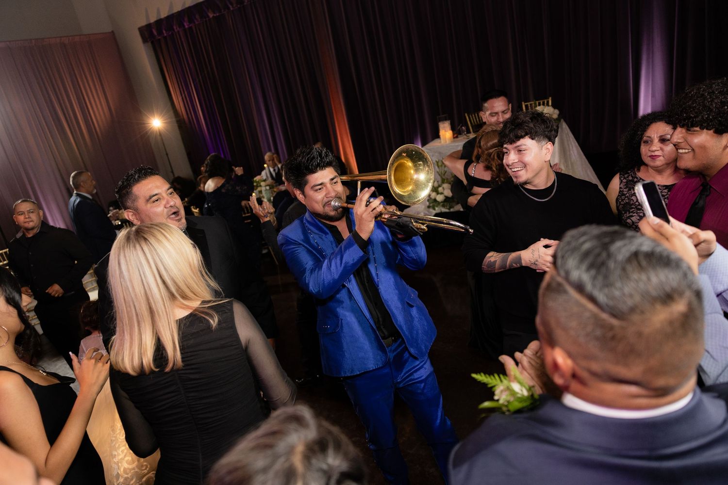 Musicians performing with brass instruments at a crowded wedding celebration.