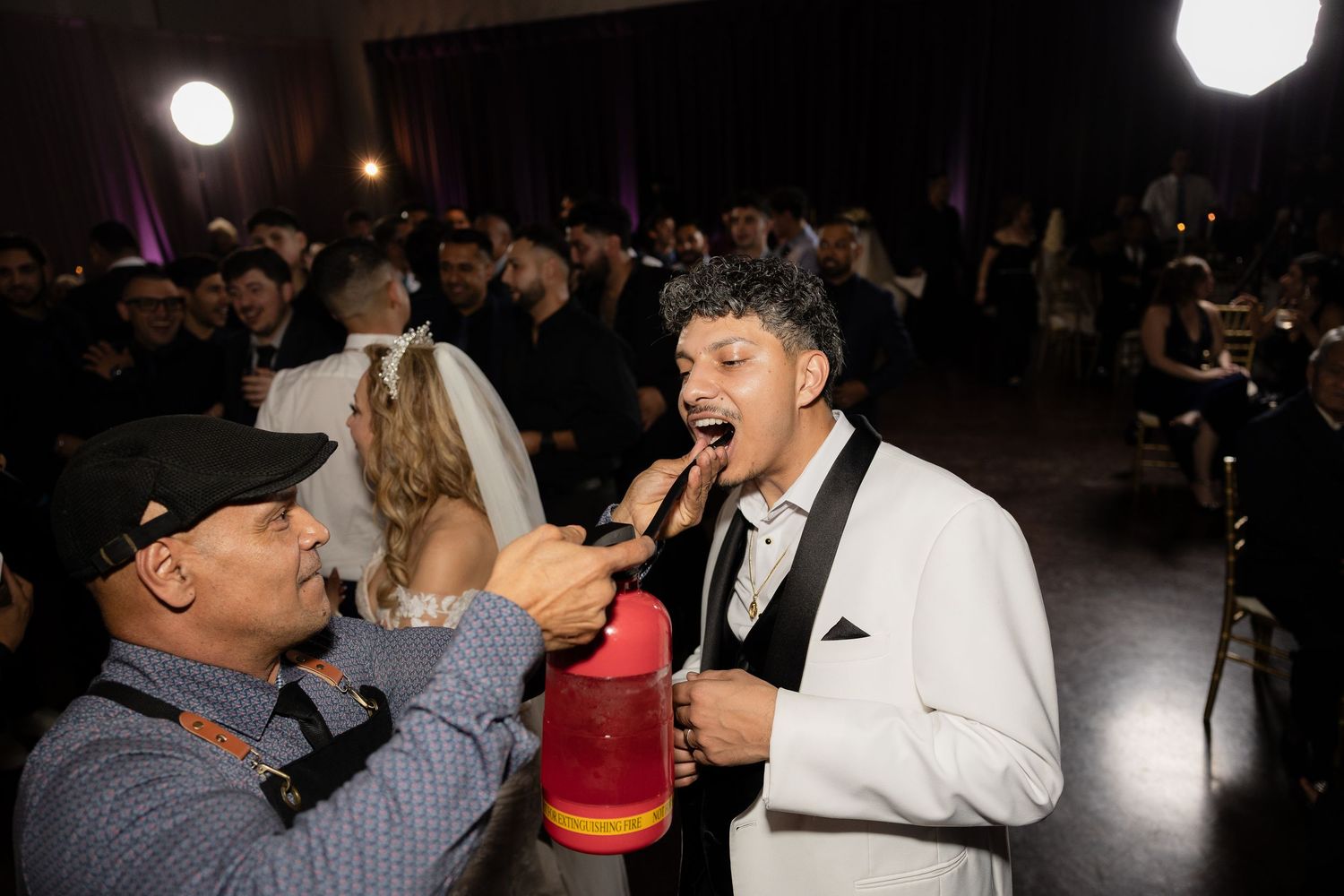 Party guests sing and celebrate with festive props at a wedding reception.