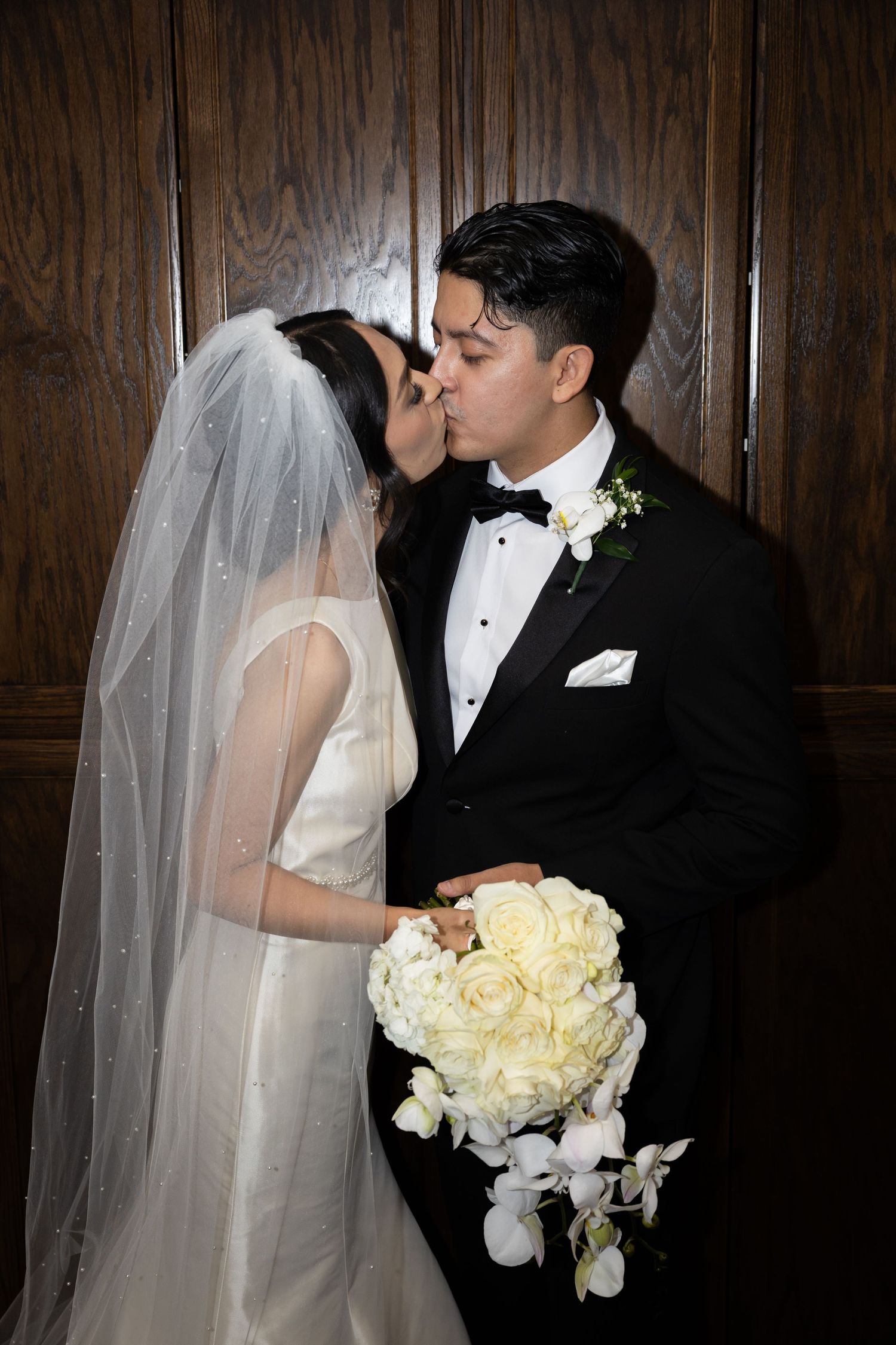 Elegant wedding portrait series against wood paneling with white floral bouquet.