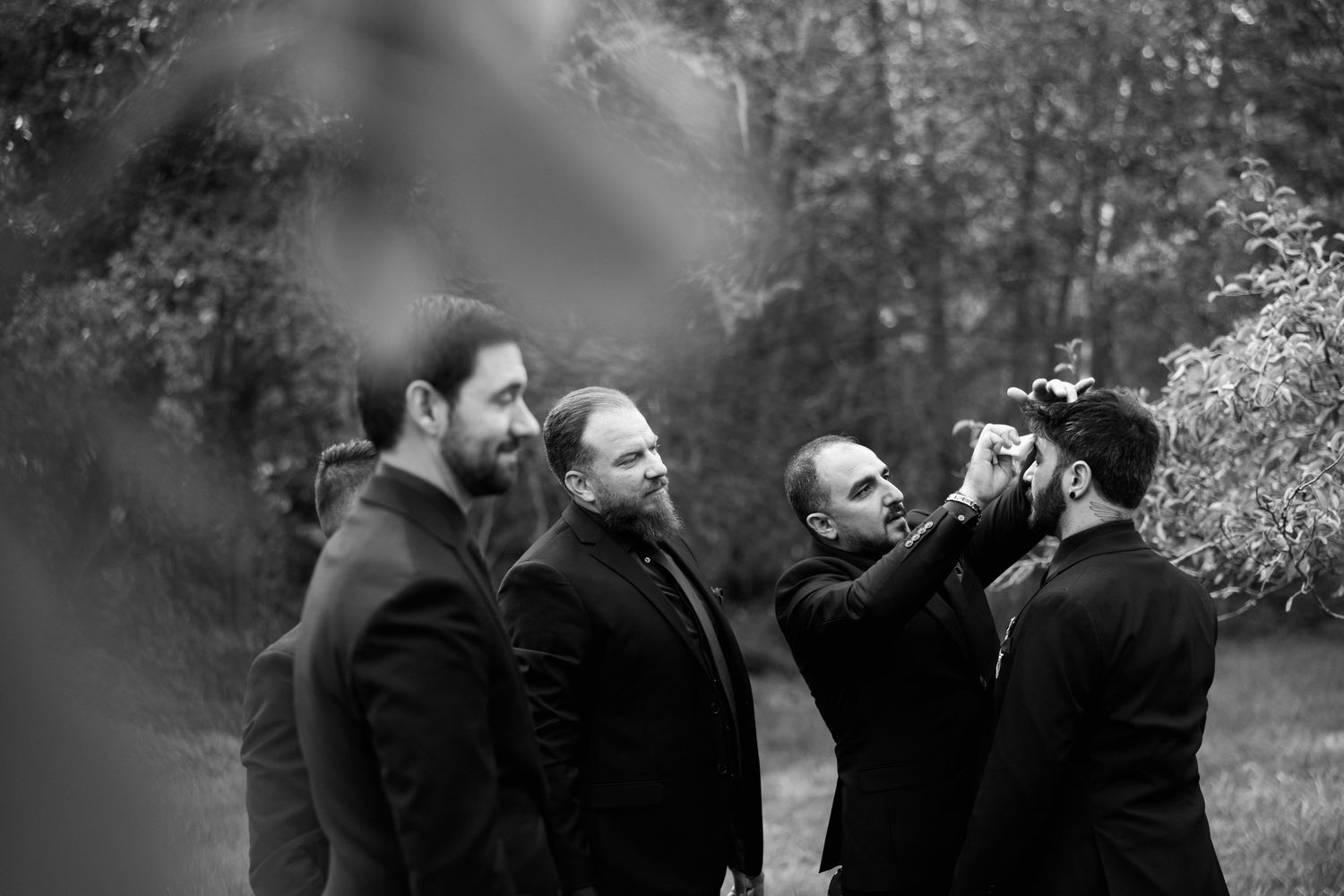 Groomsmen share laughs and jokes during outdoor wedding photo session.