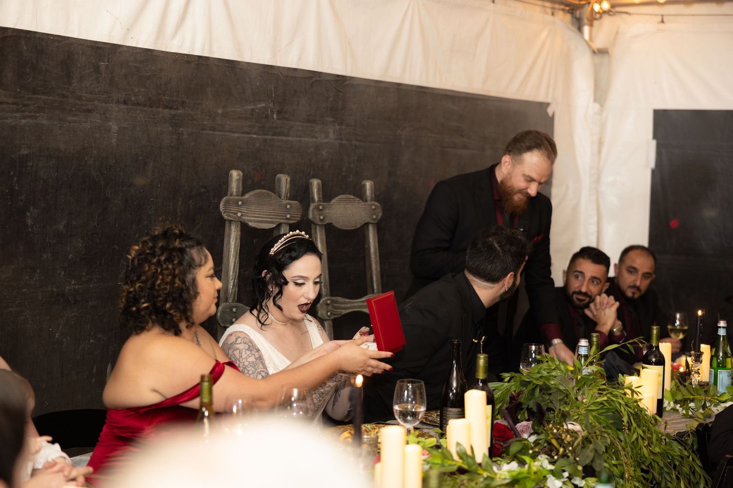 Elegant reception setup with candles and greenery decorating long dining tables.
