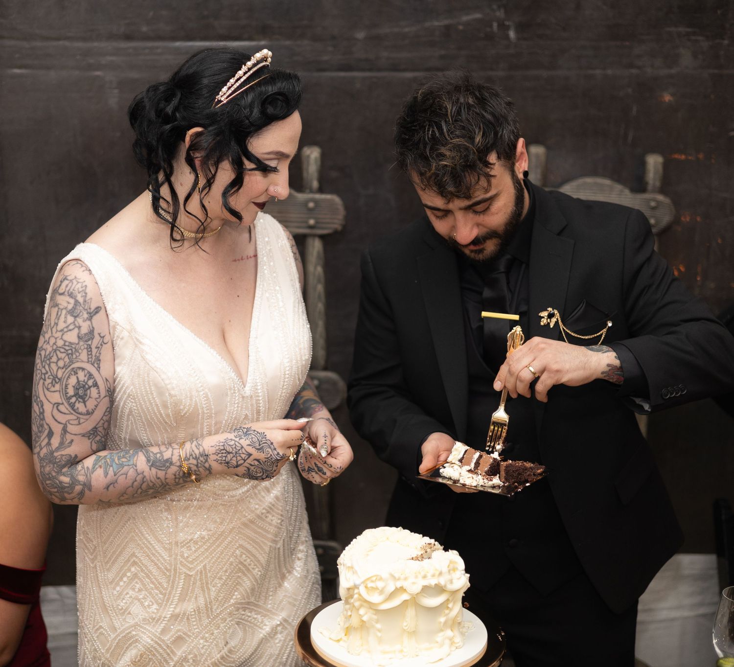 Couple cuts their white wedding cake together at a rustic reception venue.