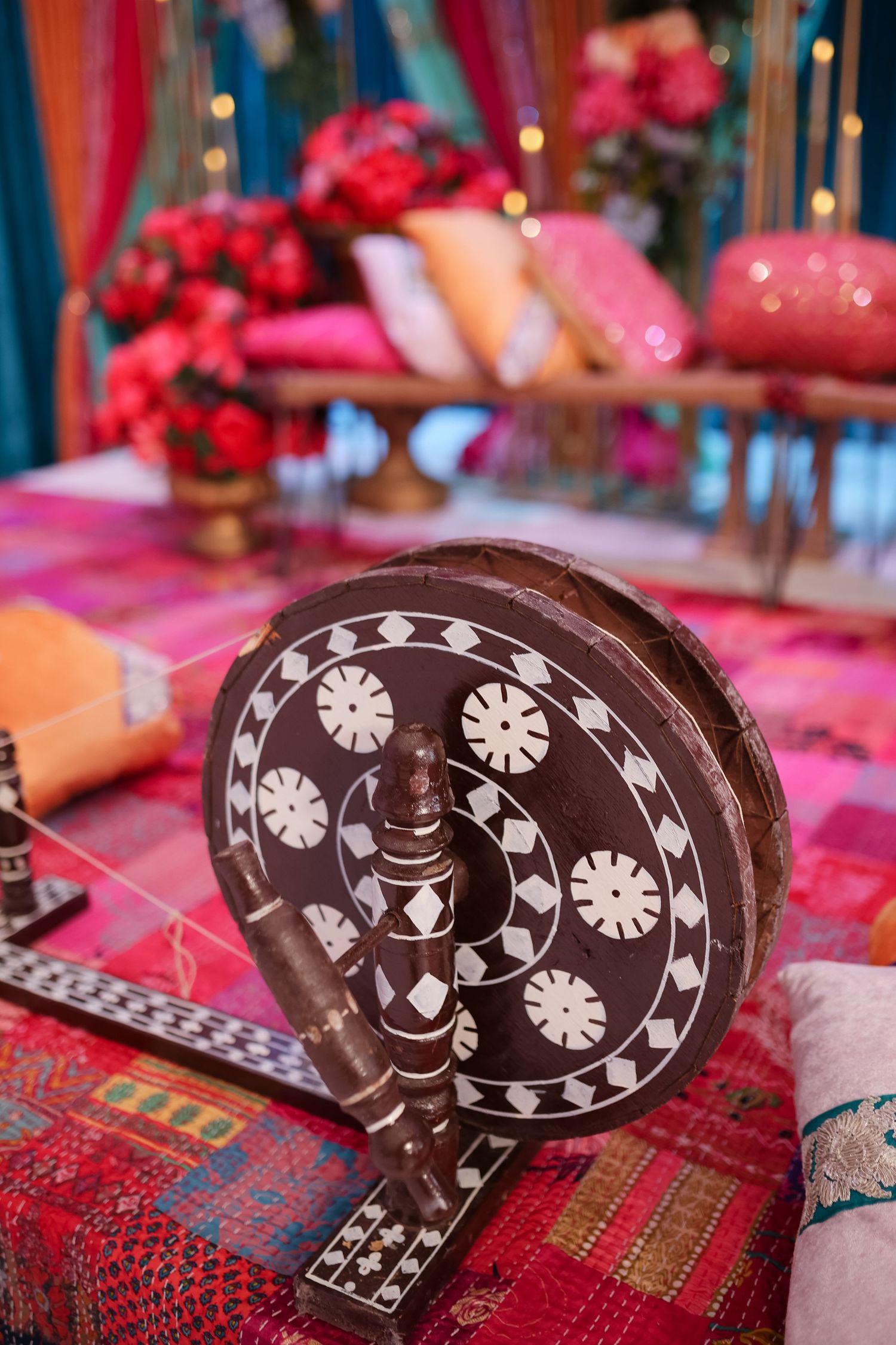 Decorative wooden elephant ornament with white inlay patterns displayed on a red patterned textile surface.