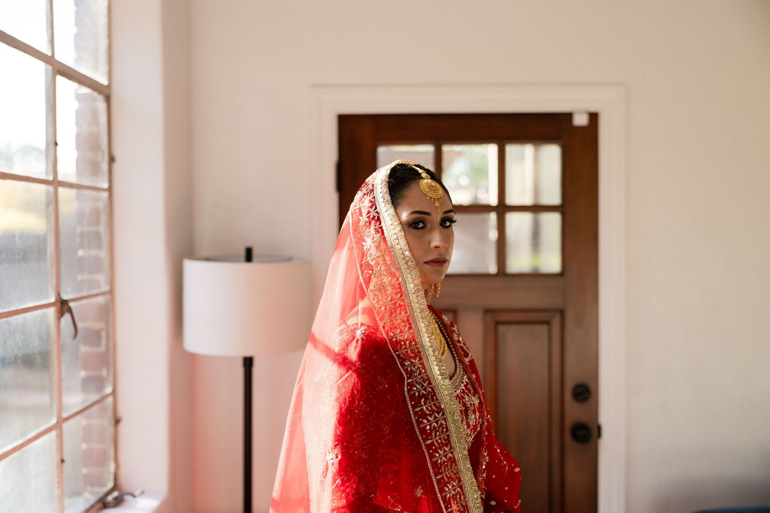 Interior wedding photography showing a bright window-lit room with elegant decor and traditional attire.