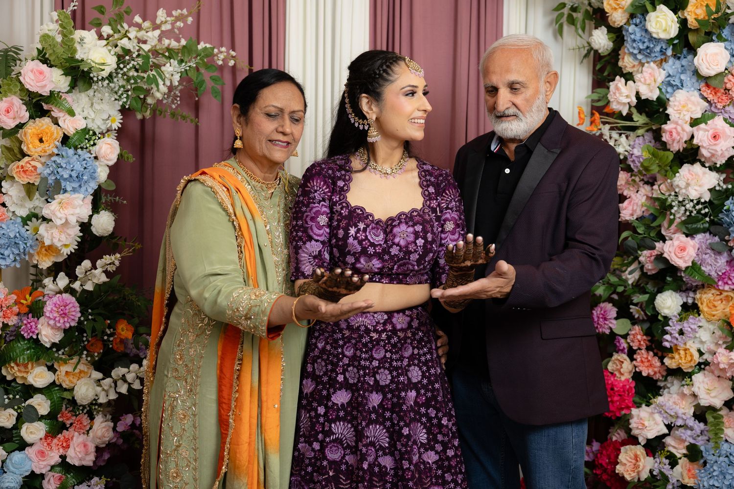 A gathering in front of a floral backdrop with traditional Indian outfits during a celebration.