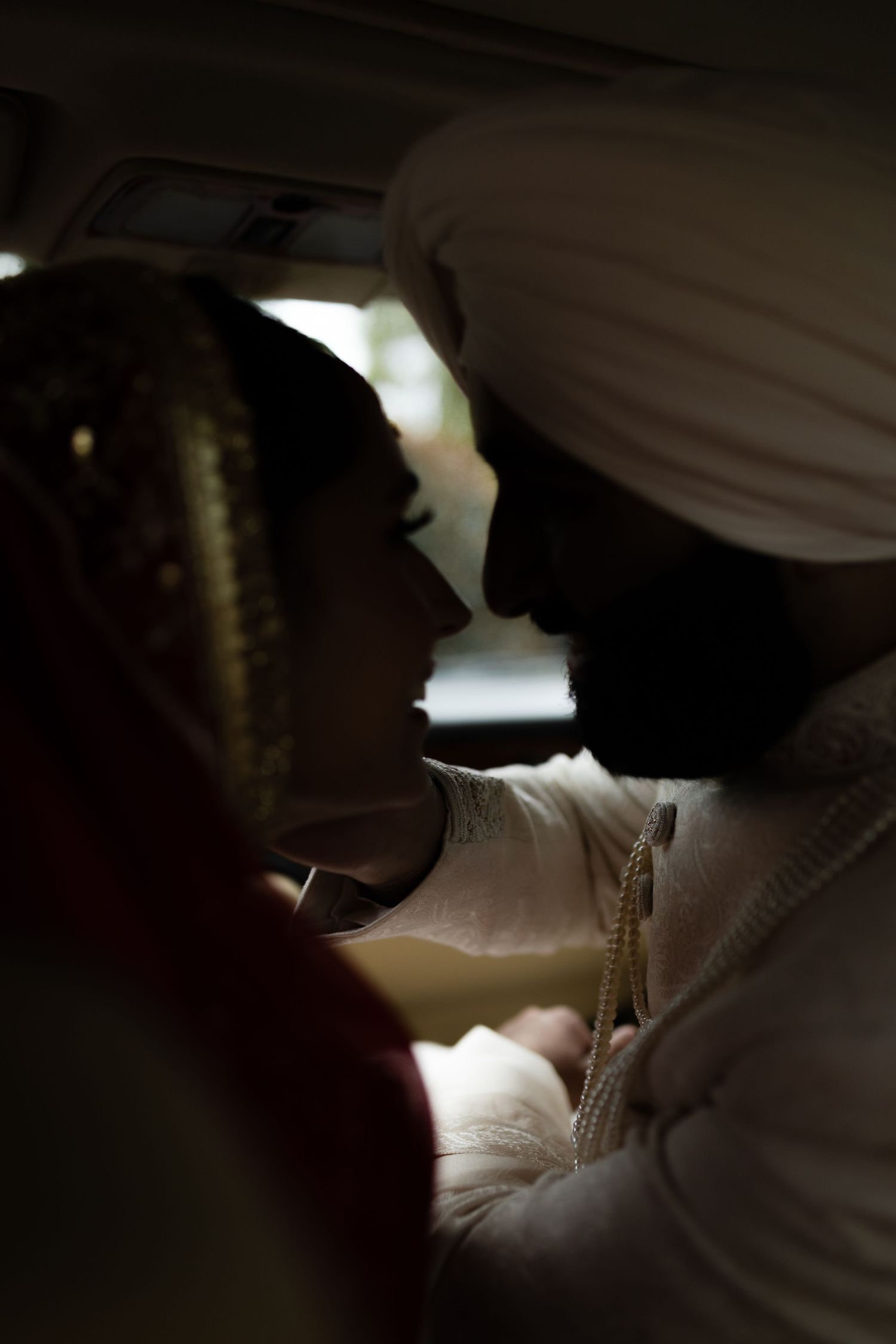 A silhouetted intimate moment captured in low light inside a car.