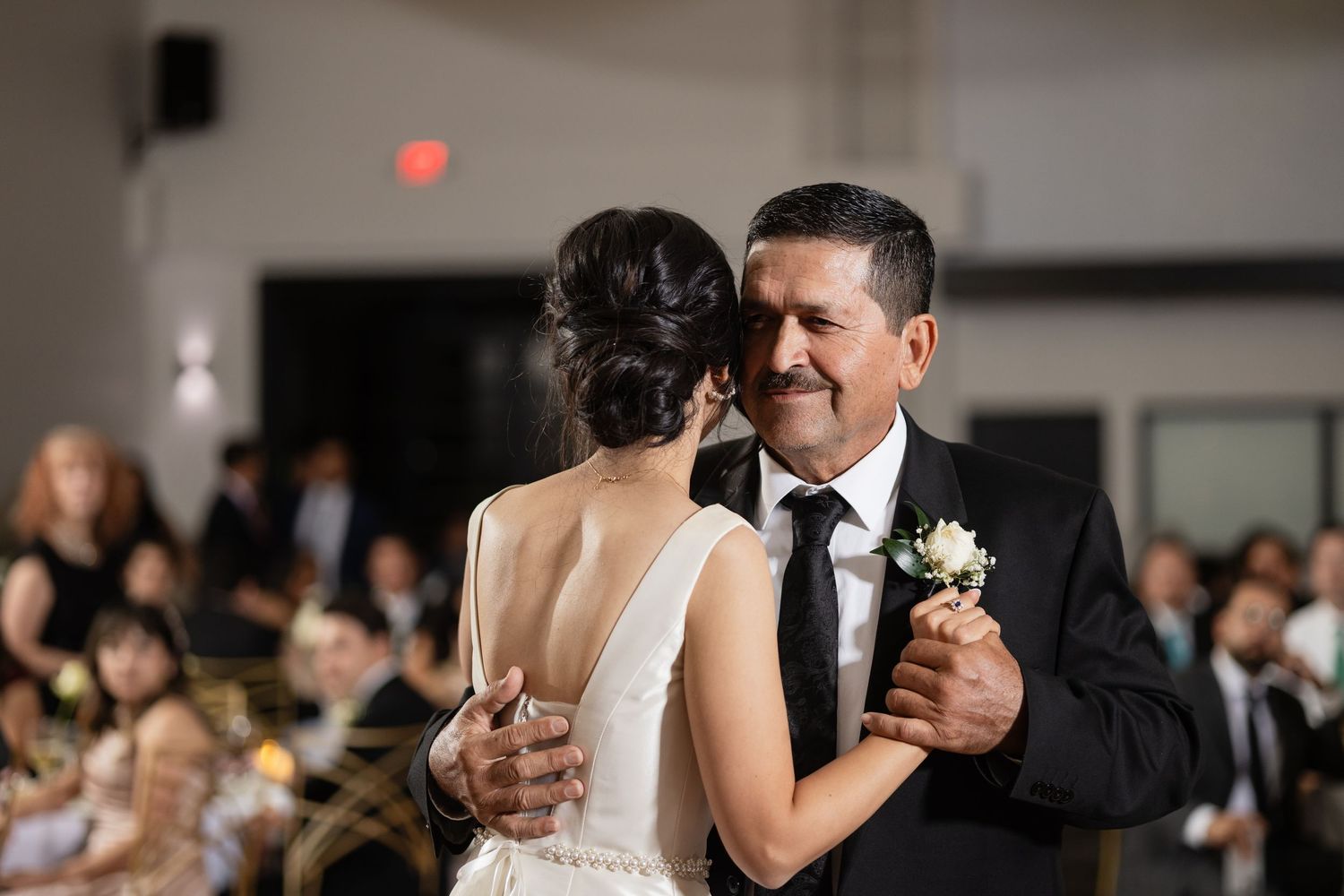 Wedding guests dance together on a reception dance floor in formal attire under indoor lighting.
