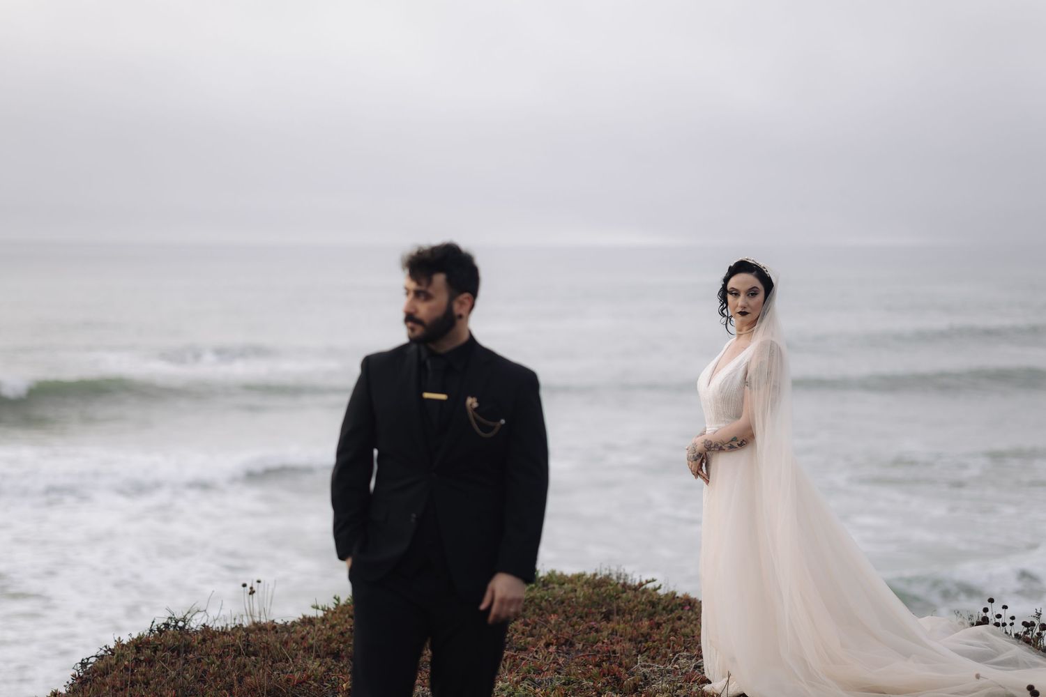 Couple standing on coastal cliffs overlooking dramatic ocean views.