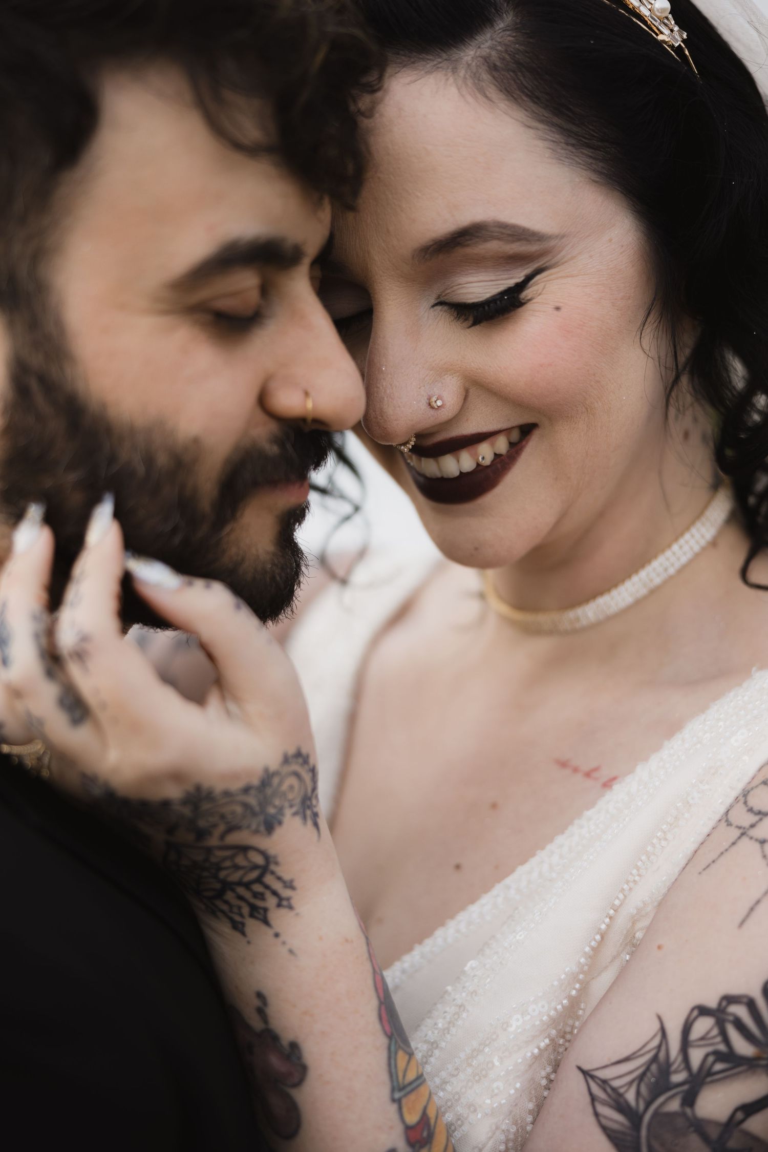 An intimate close-up portrait of a tattooed couple sharing a romantic wedding moment.