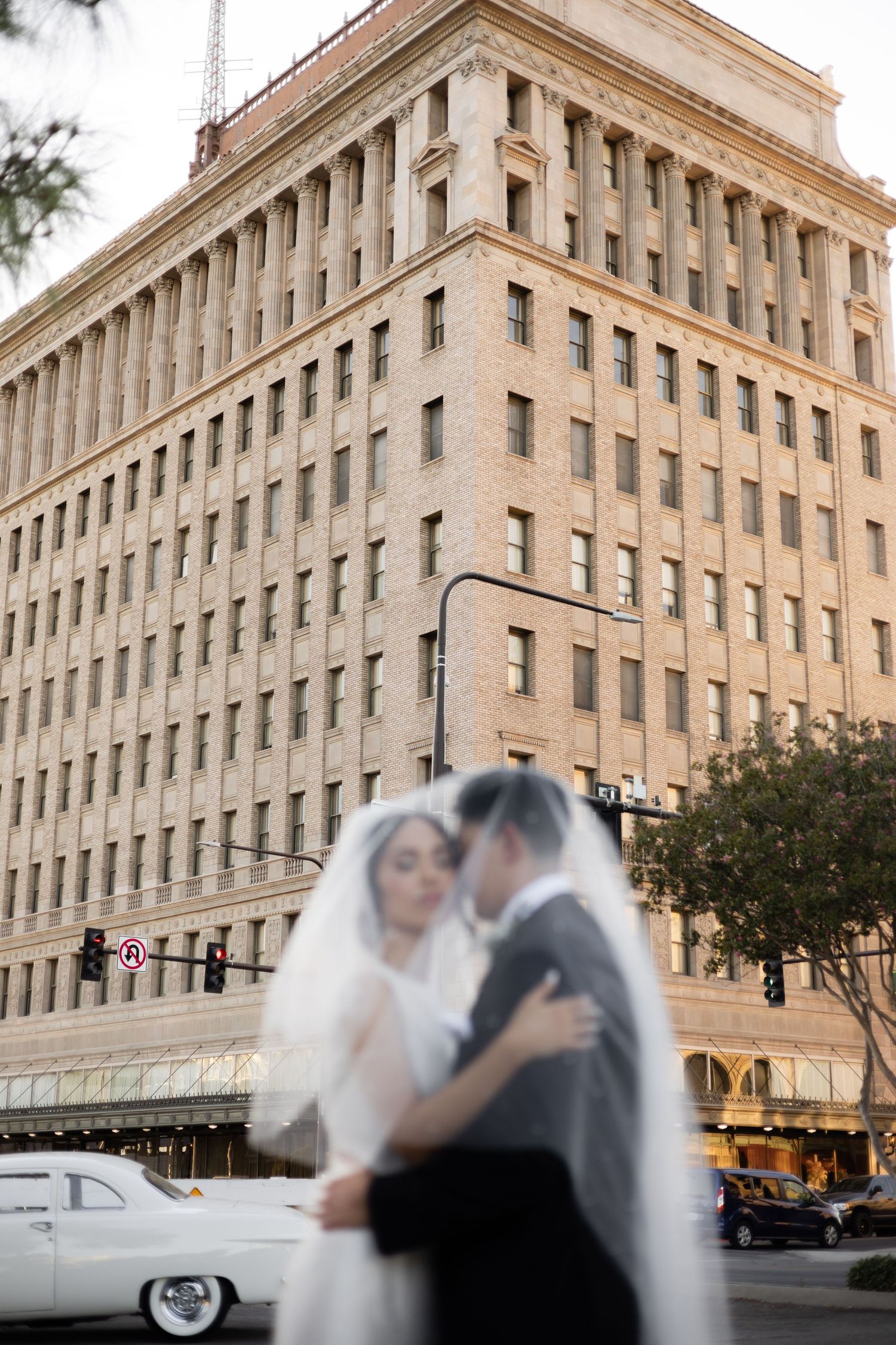 Wedding couple shares intimate moments outside an iconic downtown building at dusk.