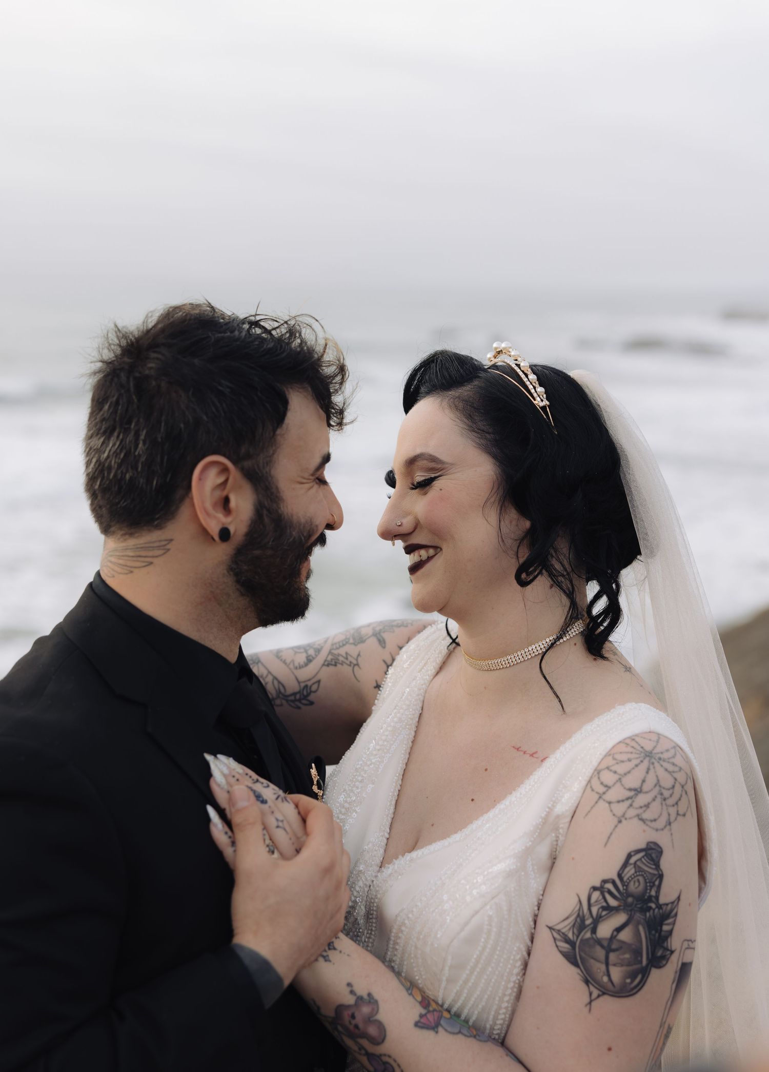 A tattooed couple shares an intimate moment during their coastal wedding photoshoot.