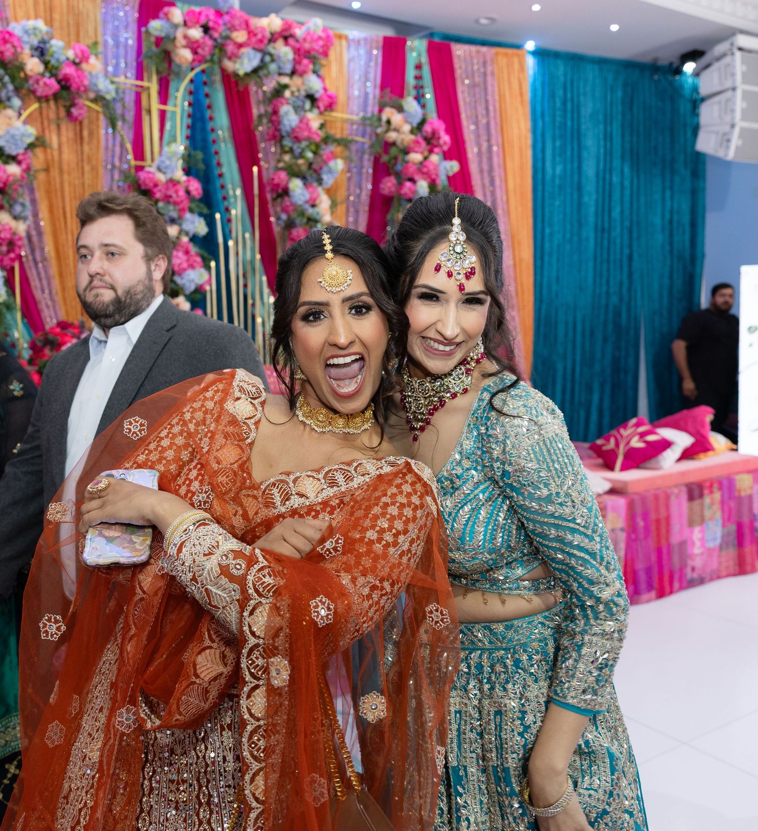 Festive wedding reception with colorful draped fabric backdrops in pink, yellow, and turquoise.