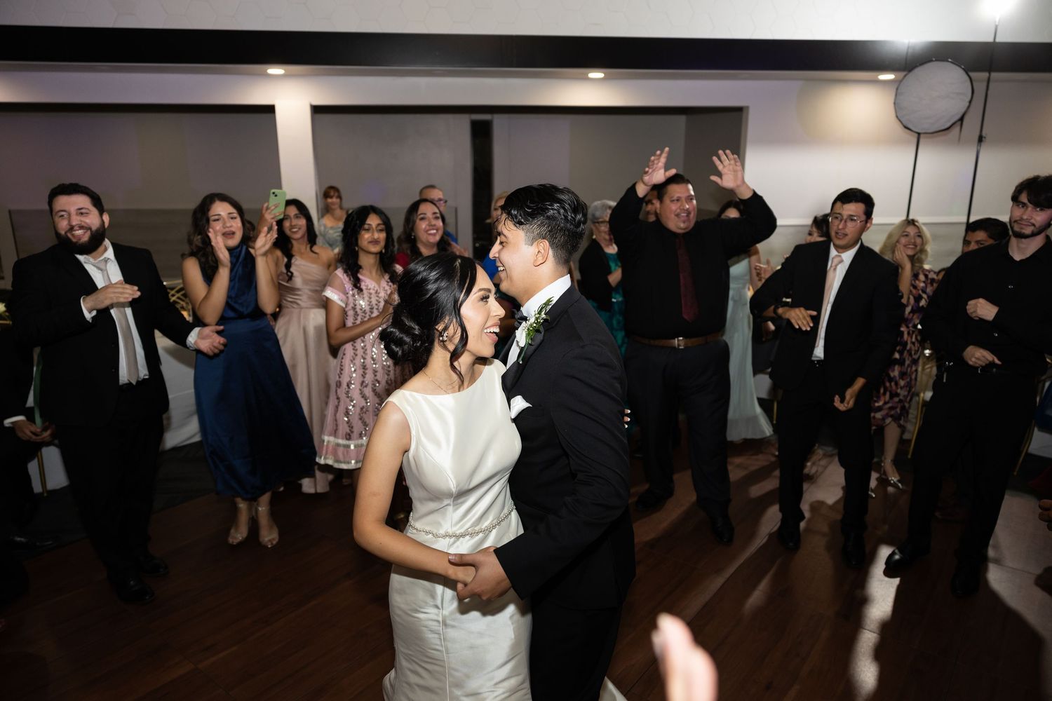Lively dance floor scene at wedding reception with guests in formal wear.