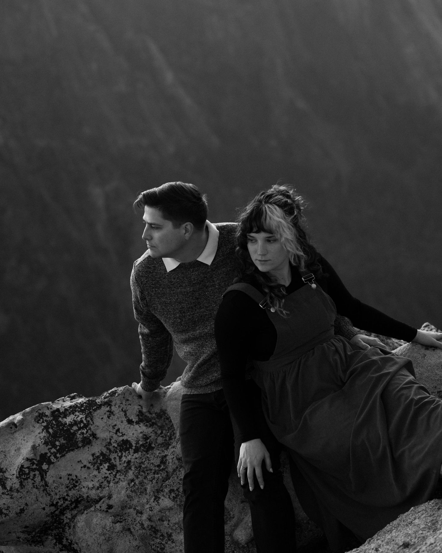 Black and white photograph of two people sharing an intimate moment on a mountain cliff.
