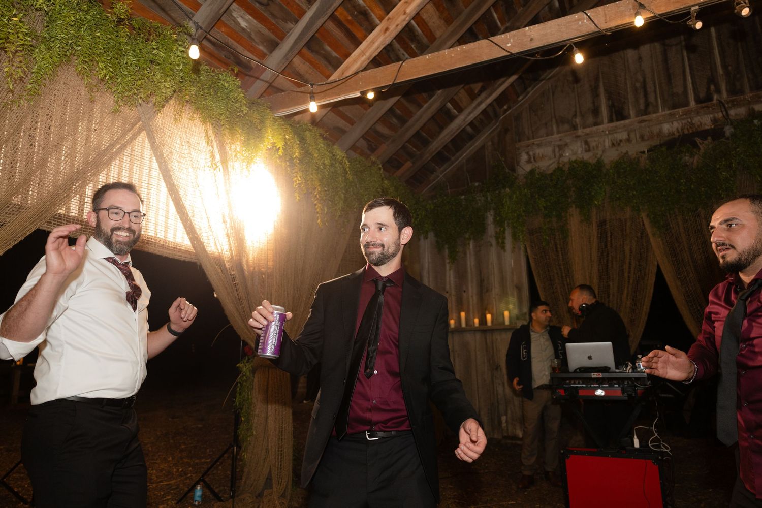 Lively dance floor scene at a rustic barn wedding reception.