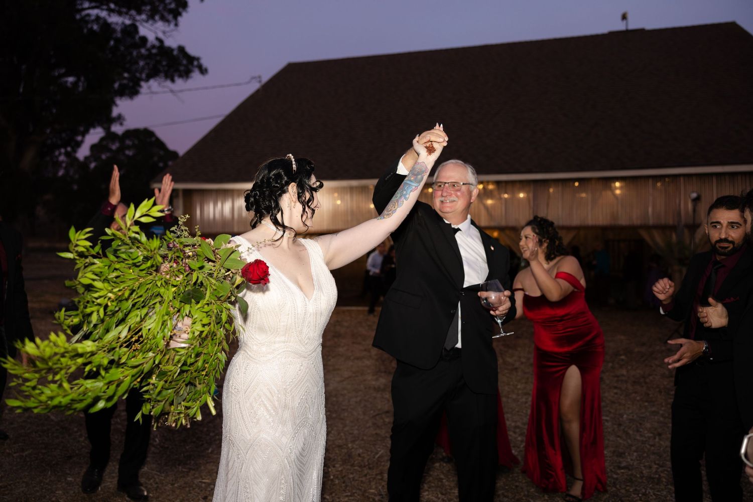 Wedding party dancing and celebrating at an outdoor evening reception.