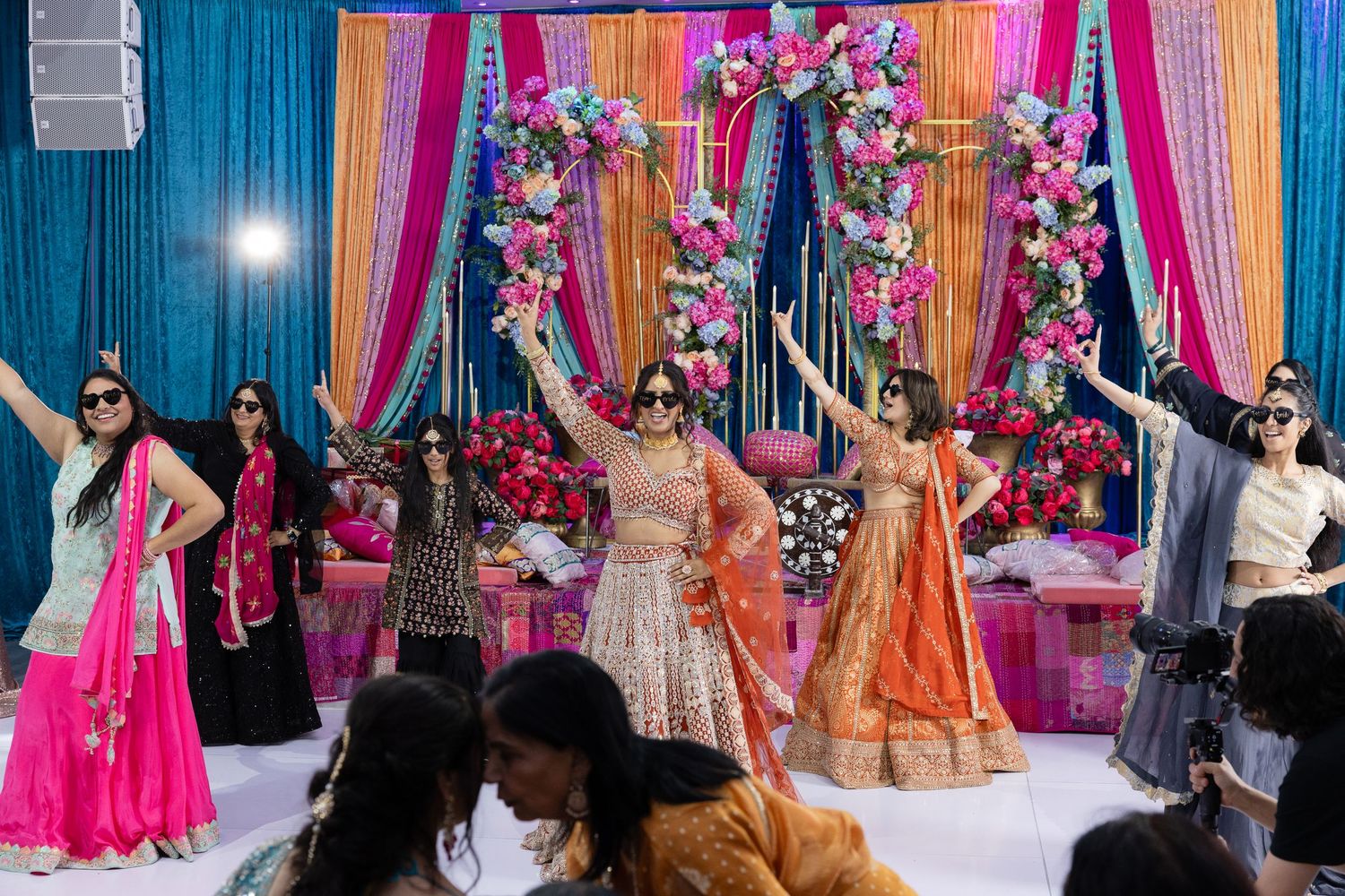 Colorful Indian wedding celebration with bright pink and orange decorations and guests dancing in traditional attire.