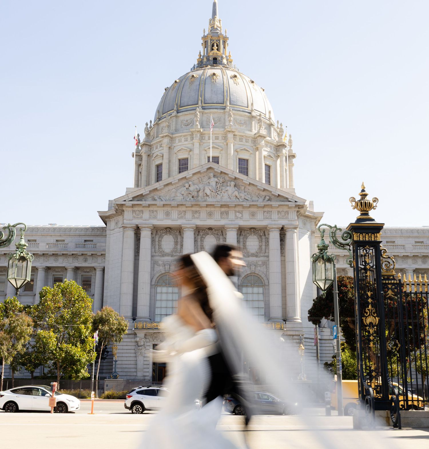 Blurred motion of people walking past San Francisco City Hall with its iconic Beaux-Arts dome architecture.