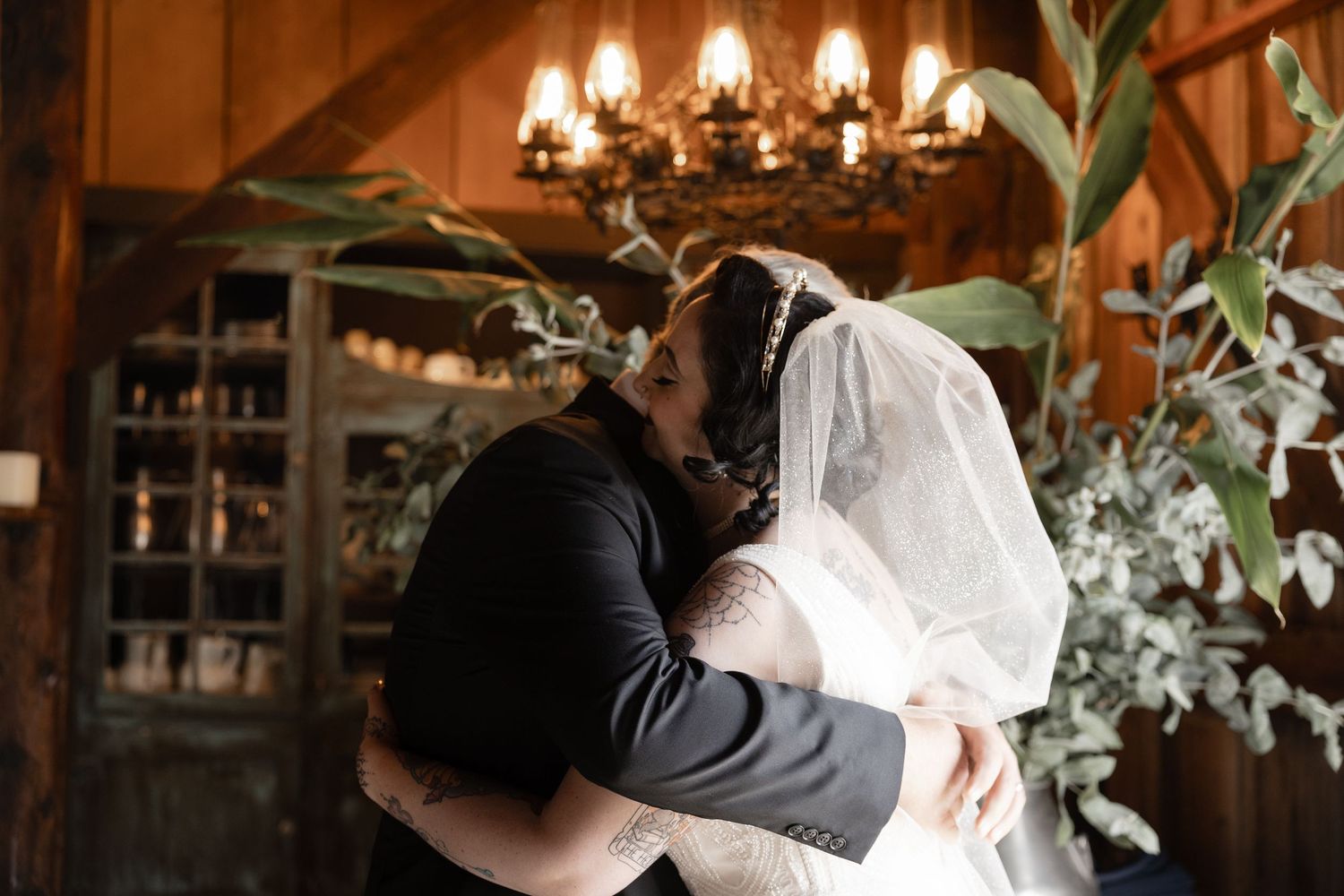 A romantic dance captured in a rustic venue with chandeliers and greenery decorations.