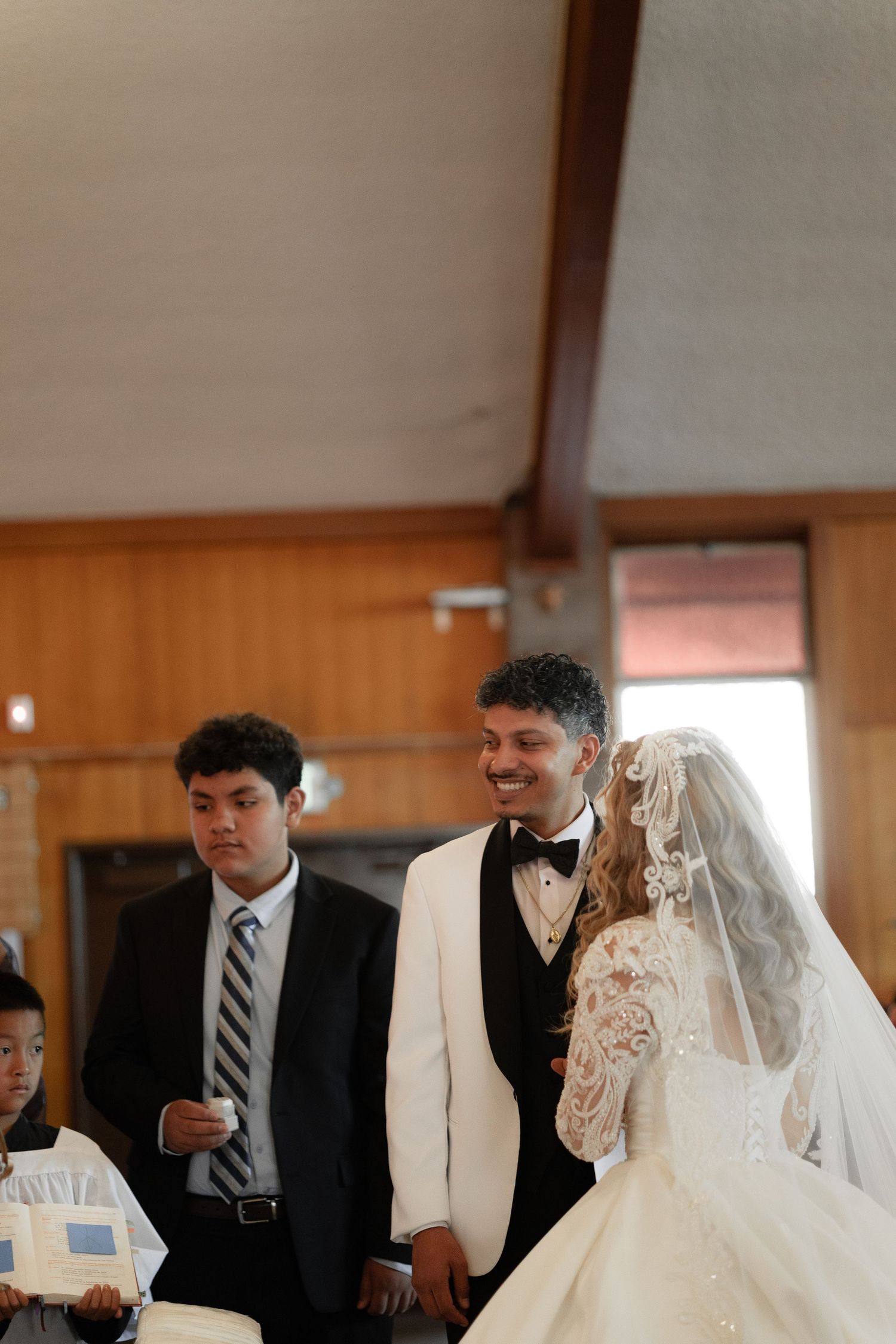 Wedding ceremony participants in formal attire standing in a church.