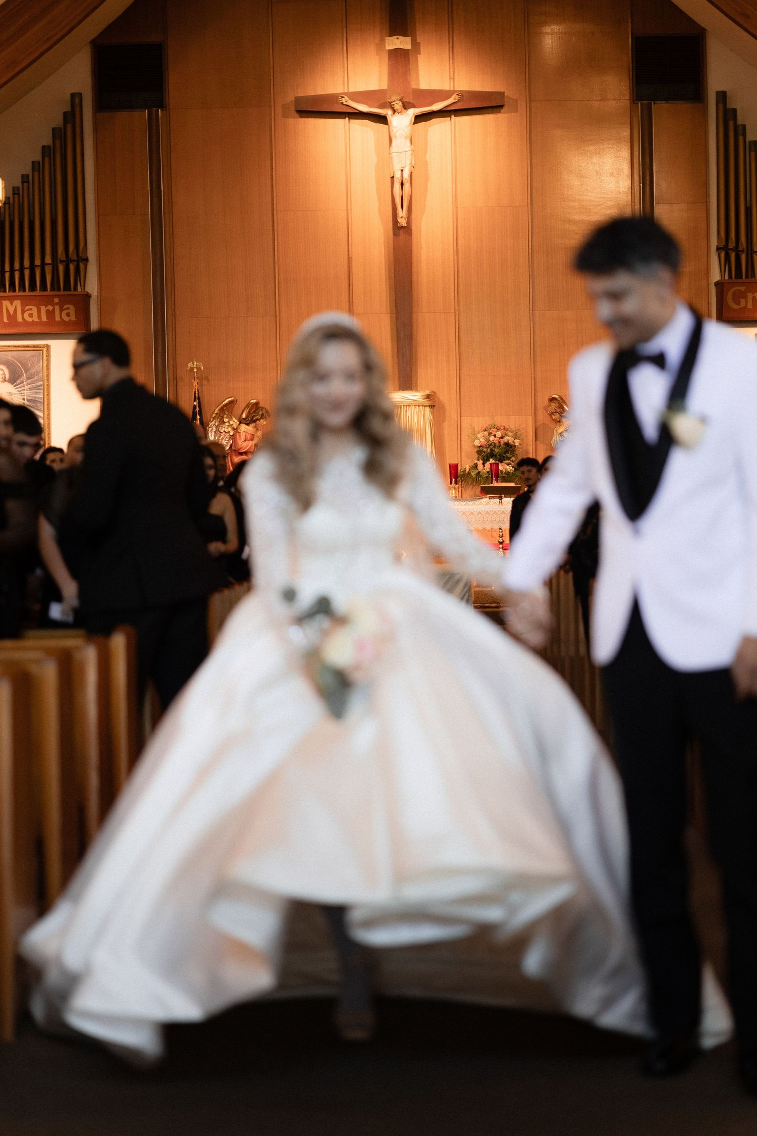 Wedding ceremony in church with illuminated crucifix and couple in traditional attire.