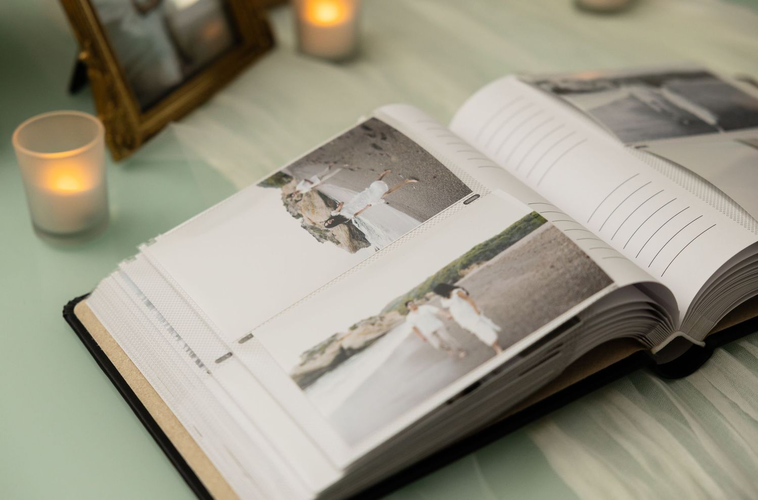 Wedding photo album displayed on mint green table with glowing candles.