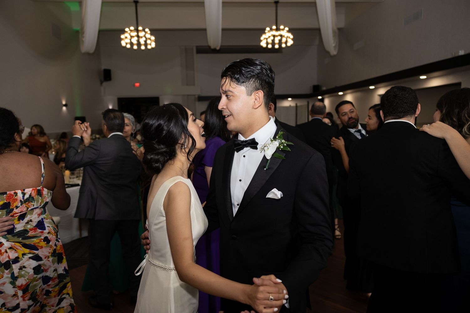 Wedding reception dance floor scene with guests in formal attire enjoying the celebration.