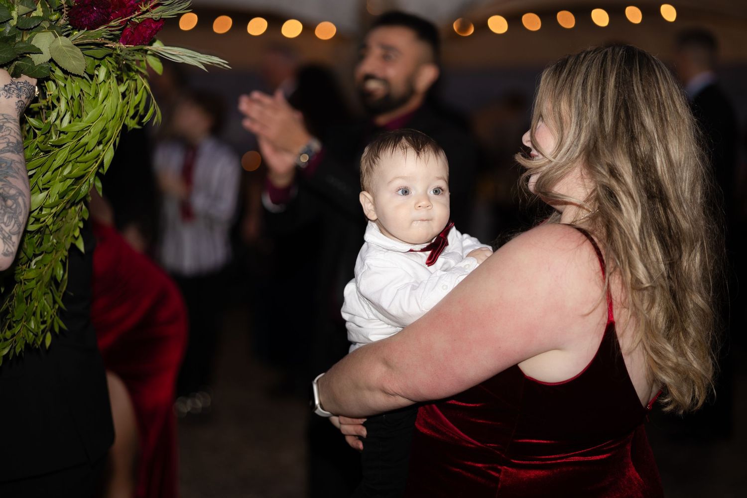 Wedding guests embrace while dancing at an evening reception.