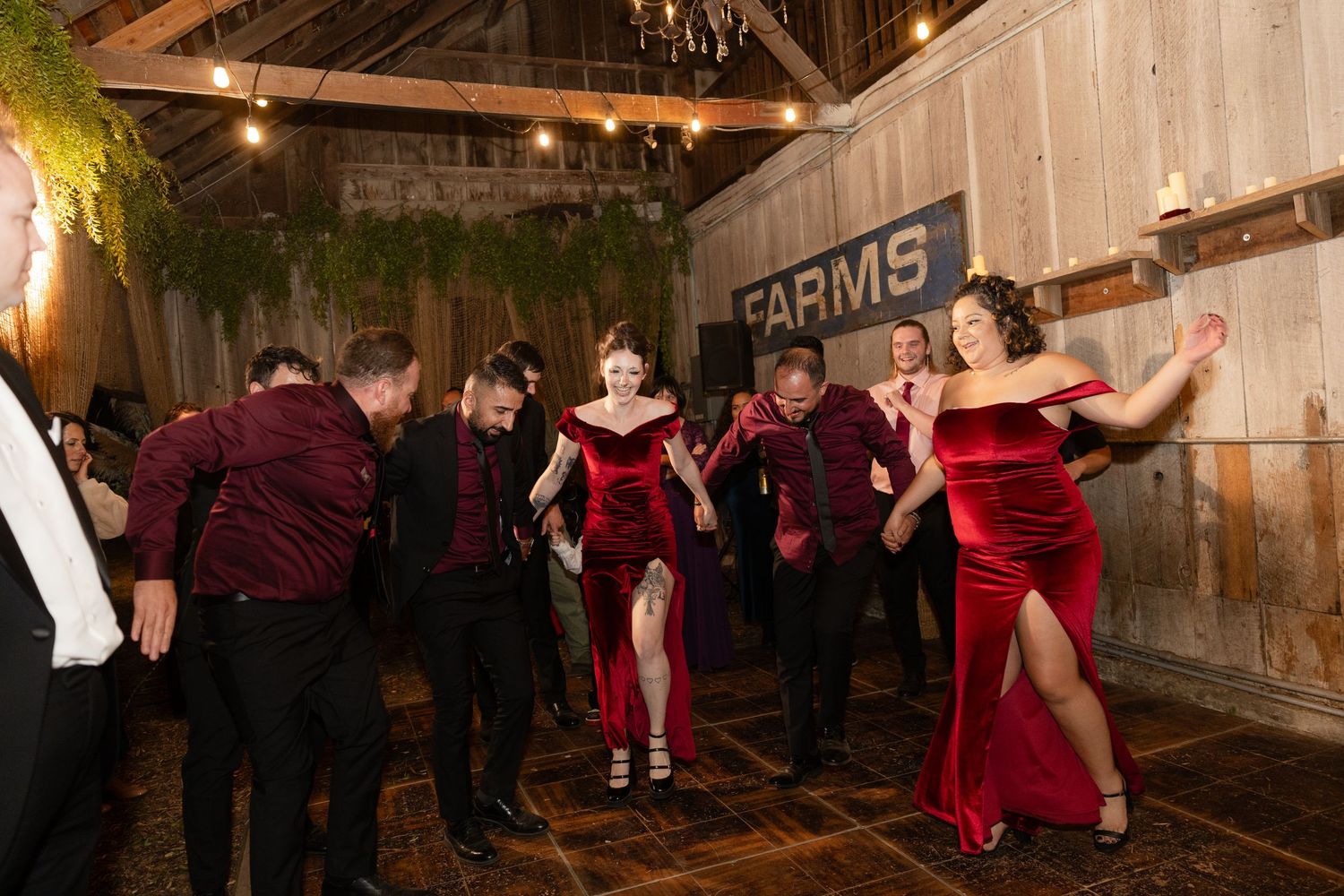 Guests dancing and celebrating at a rustic barn wedding reception with string lights overhead.