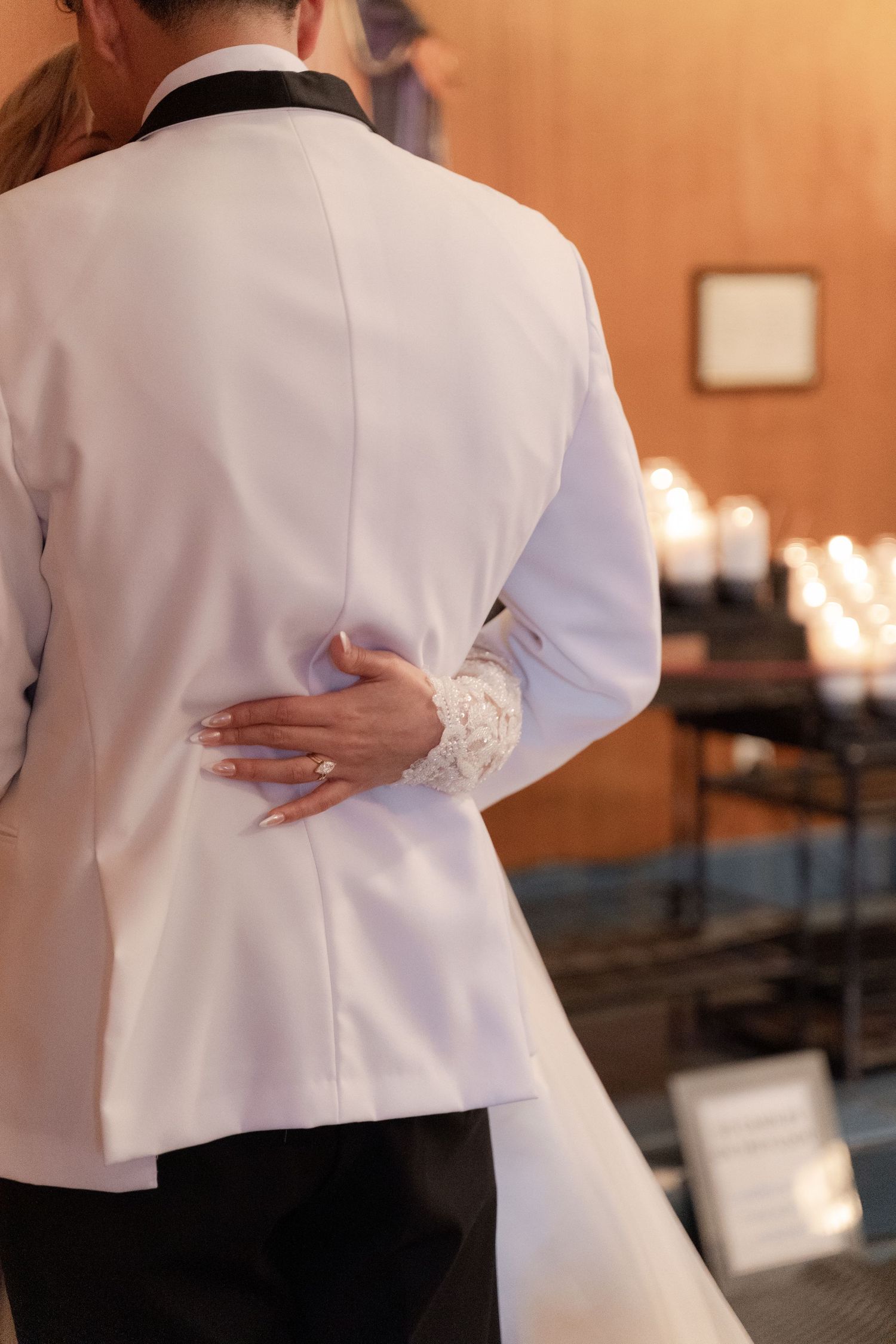 Close-up of white formal attire with hands clasped behind back during ceremony.
