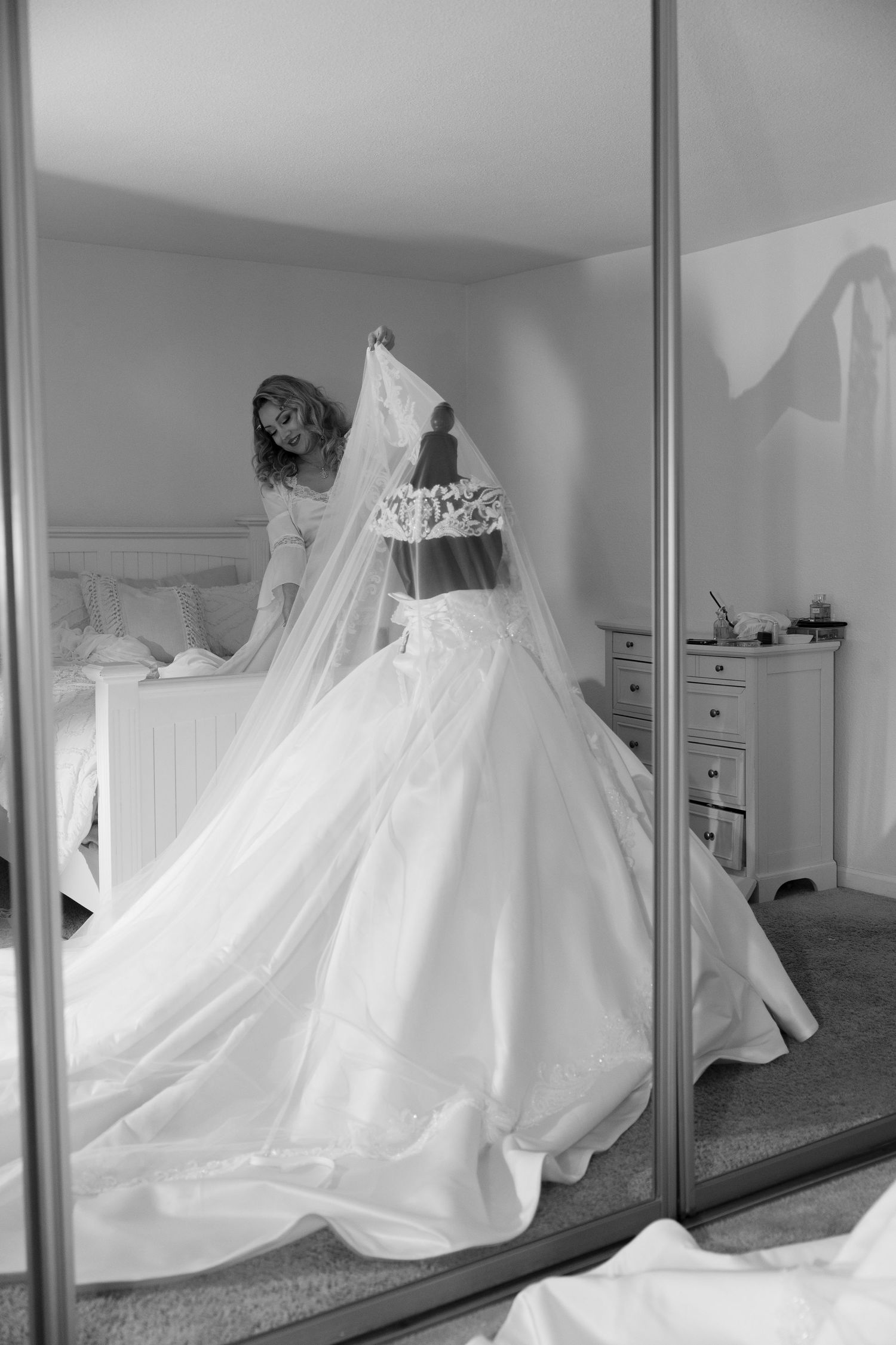 Elegant white wedding dresses displayed in a room with mirrored closet doors showing their reflection.