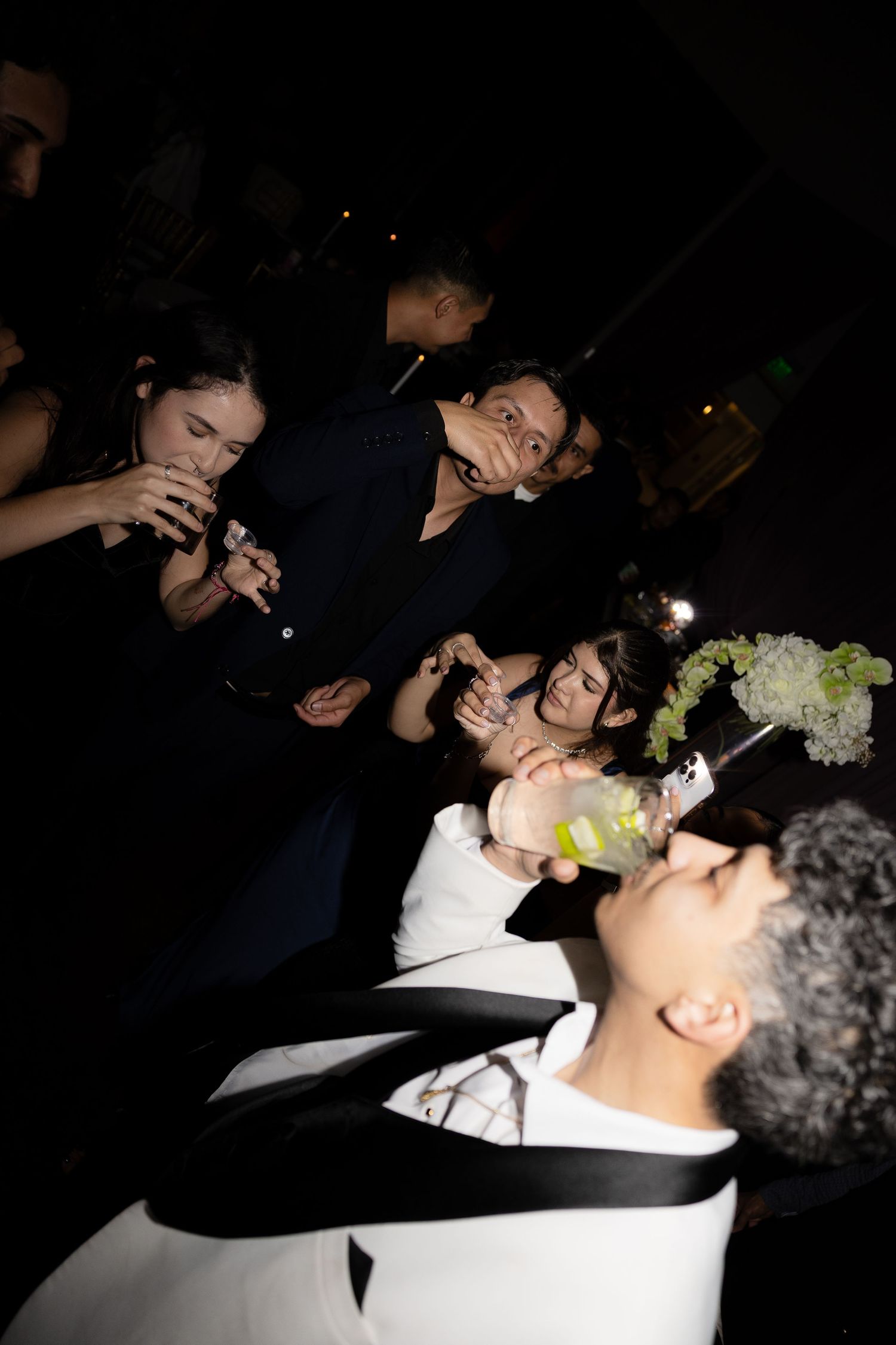 Wedding celebration candid shots showing guests enjoying festivities in dark lighting.