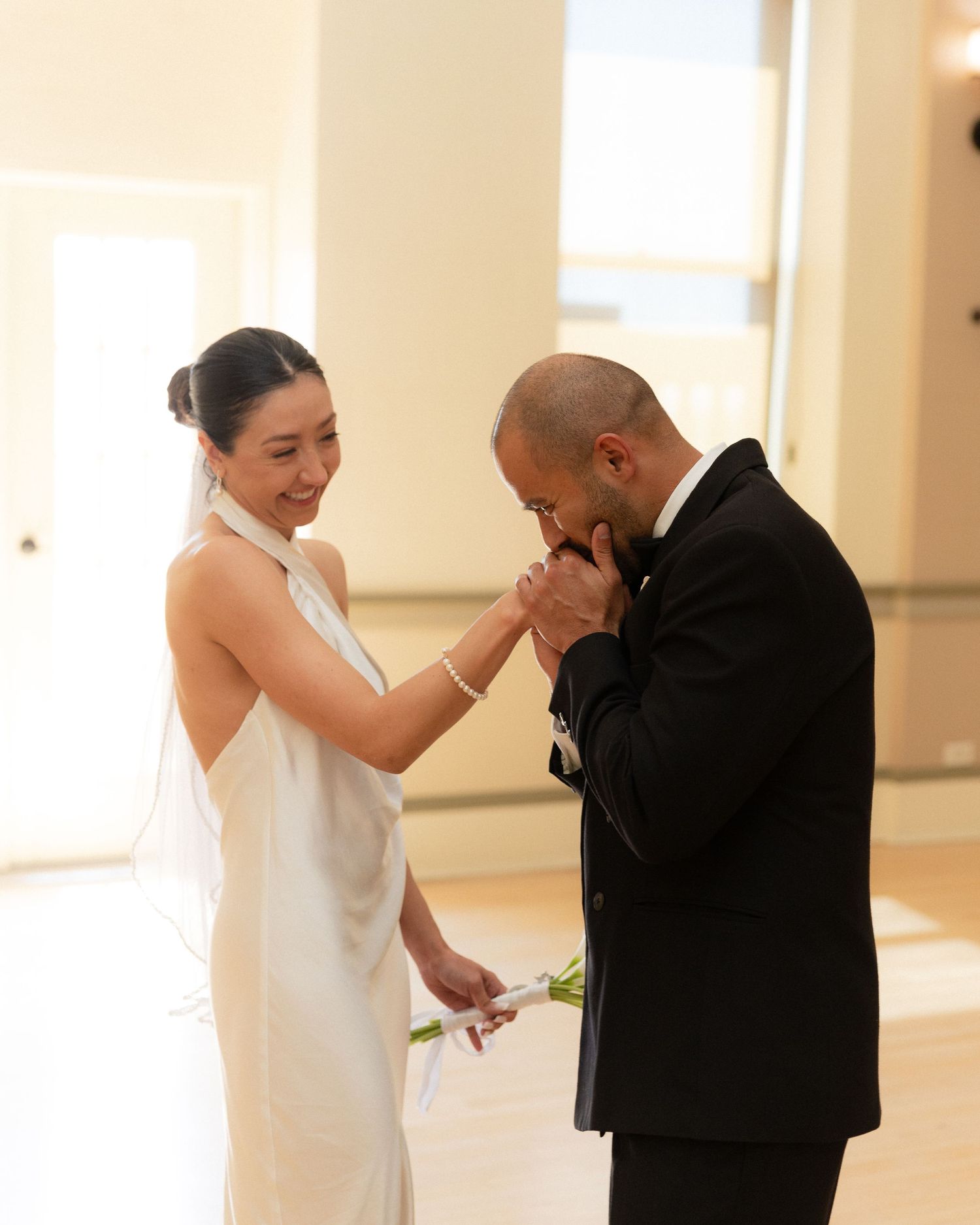 A tender moment between a bride in a white dress and groom in a black tuxedo during their wedding ceremony.