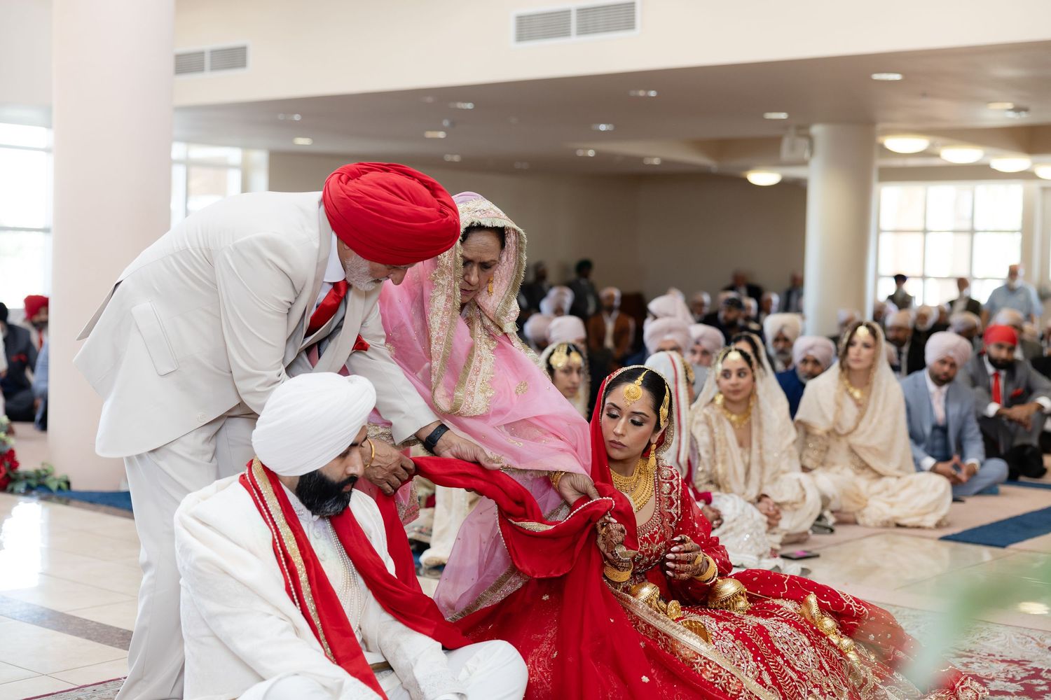 Traditional Sikh wedding ceremony taking place in a bright indoor venue.