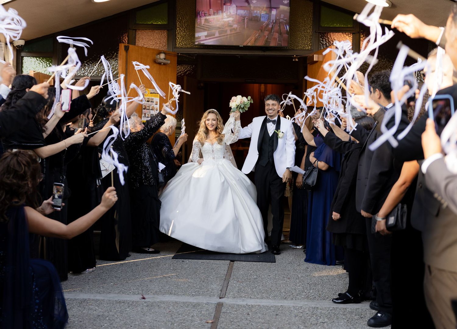 Wedding guests line up outside creating a celebratory exit tunnel with sparklers for the newlyweds.