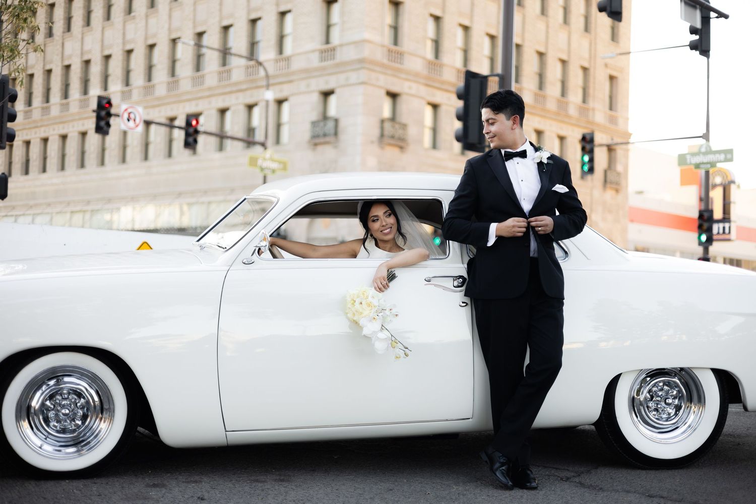 Vintage white automobile with chrome wheels serves as elegant wedding day transportation.