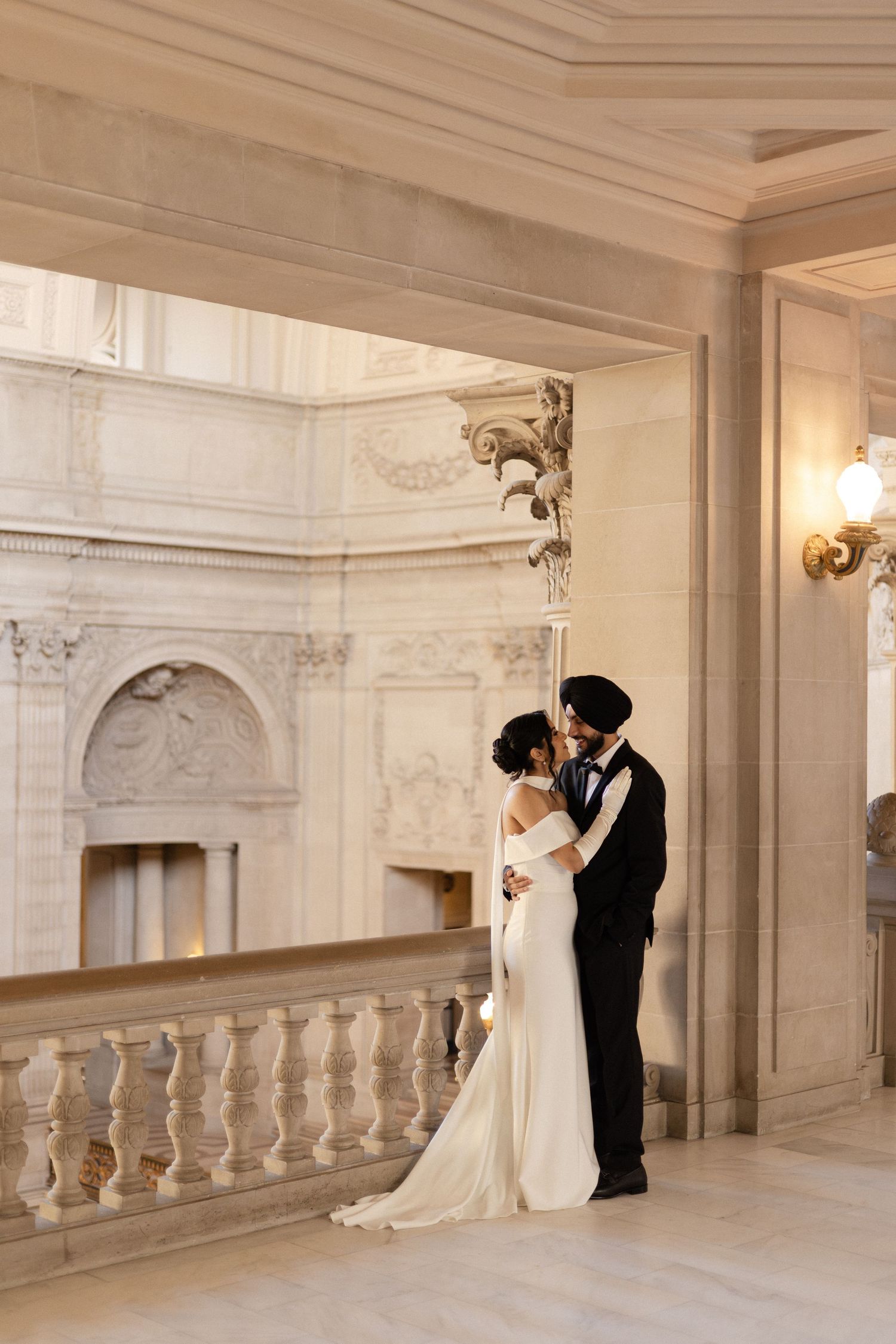 A wedding photoshoot in a grand marble hallway with ornate balustrades and columns.