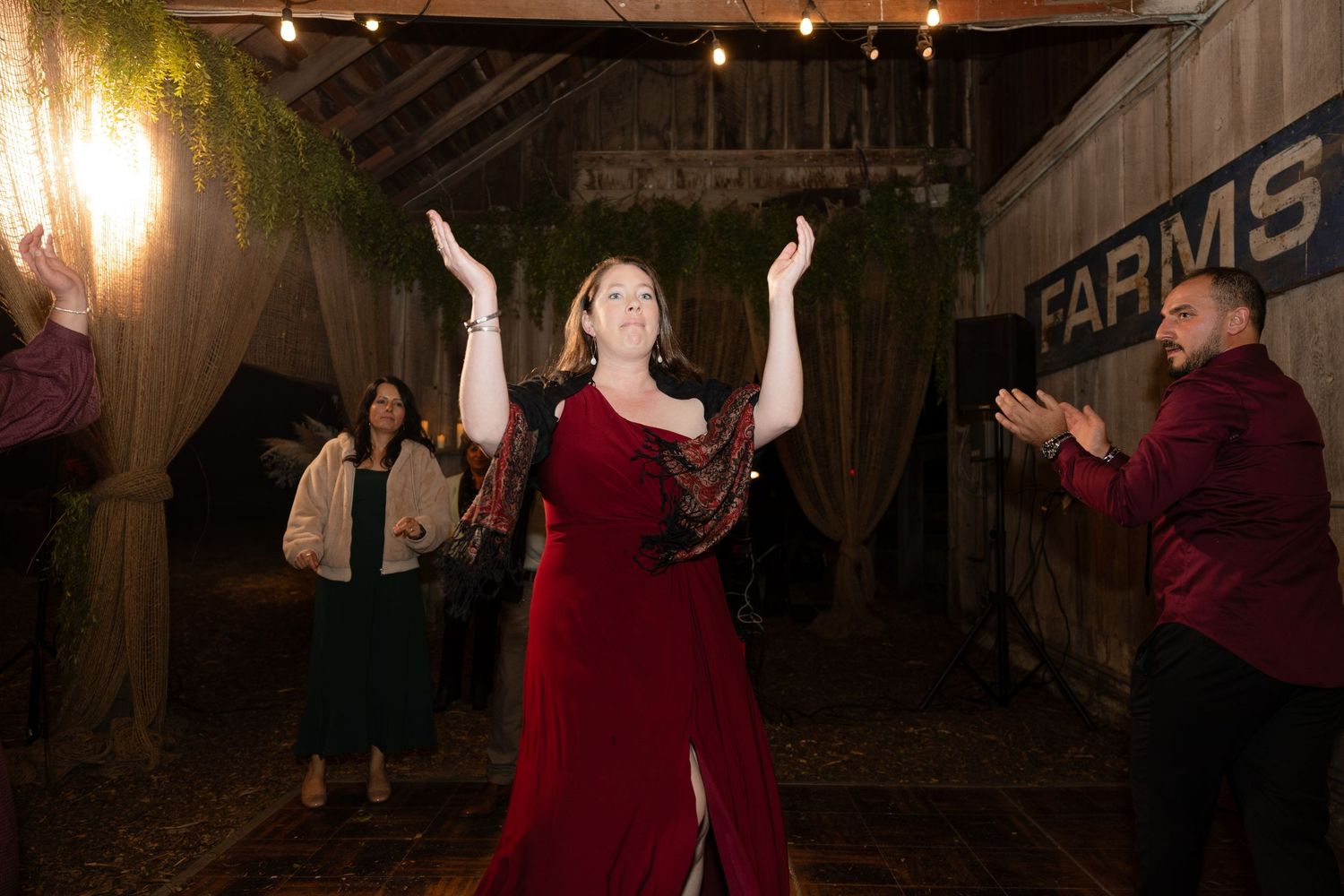 Guests enjoying a lively dance party under warm string lights at an indoor barn venue.
