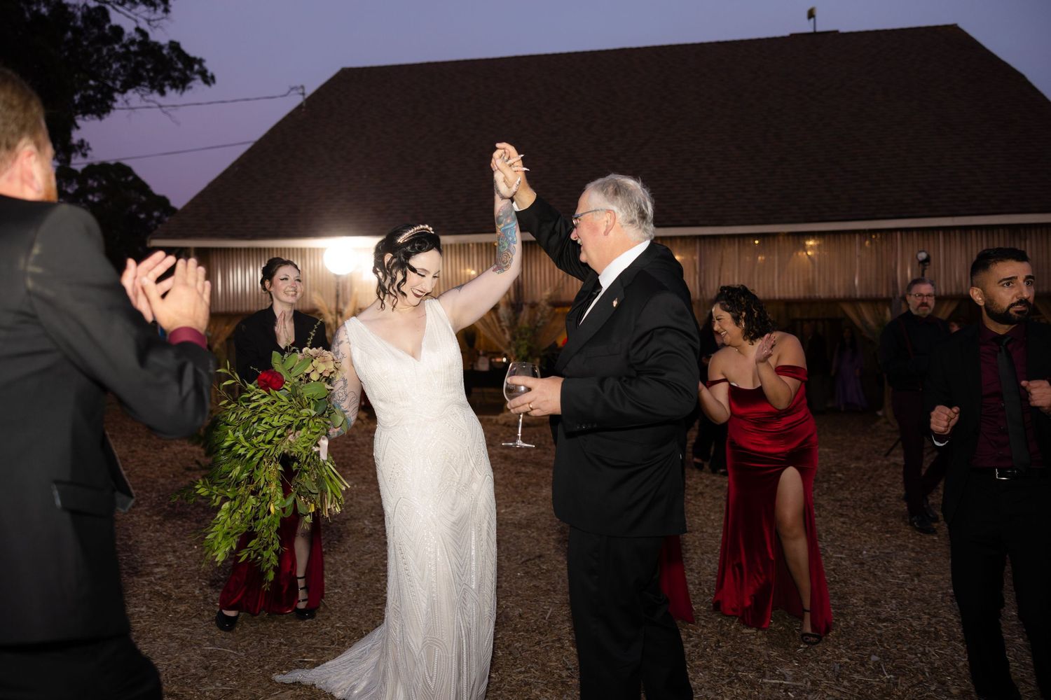 Outdoor wedding reception with guests dancing under evening sky.