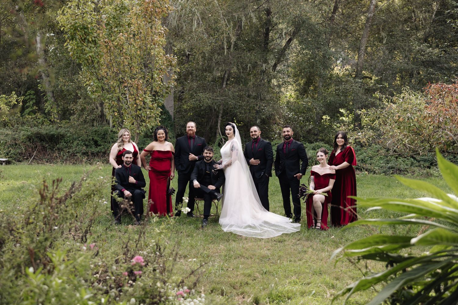 Wedding party posed in natural outdoor setting with fall colors and greenery.